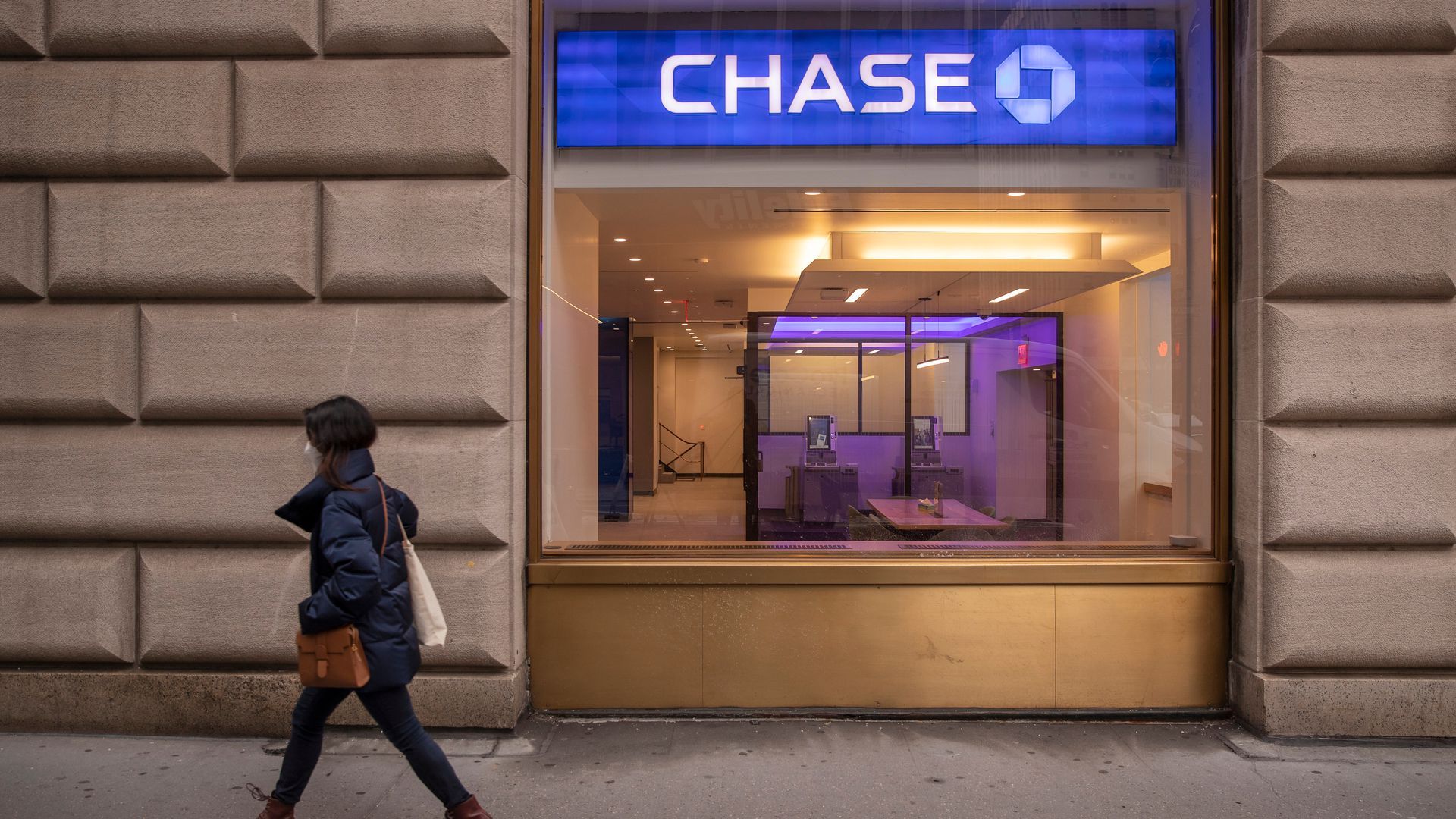 A person walks on the sidewalk alongside a Chase bank sign.