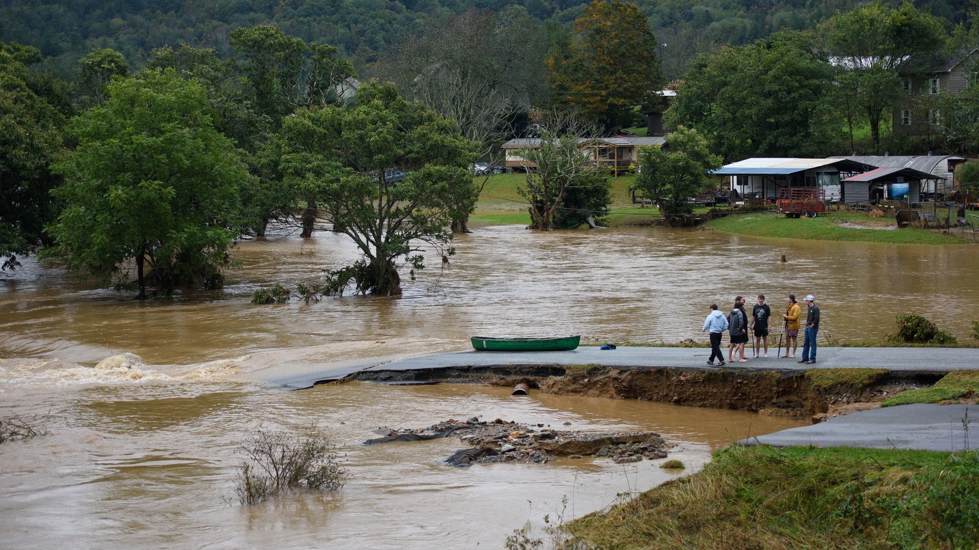 People stand on the edge of a flooded road near Boone, North Carolina in the wake of Hurricane Helene.