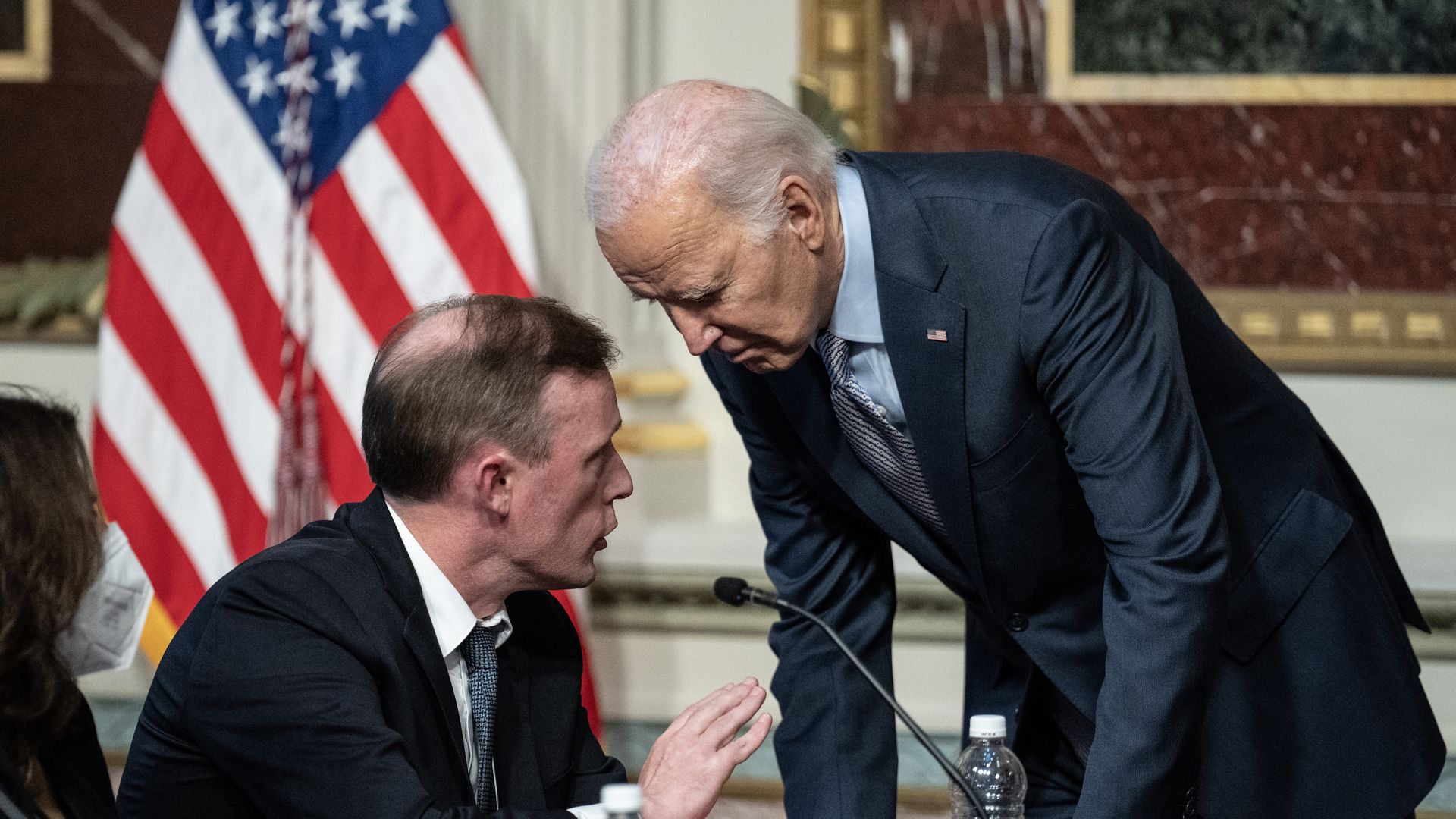 Biden se inclina sobre Sullivan, quien le habla al oído.