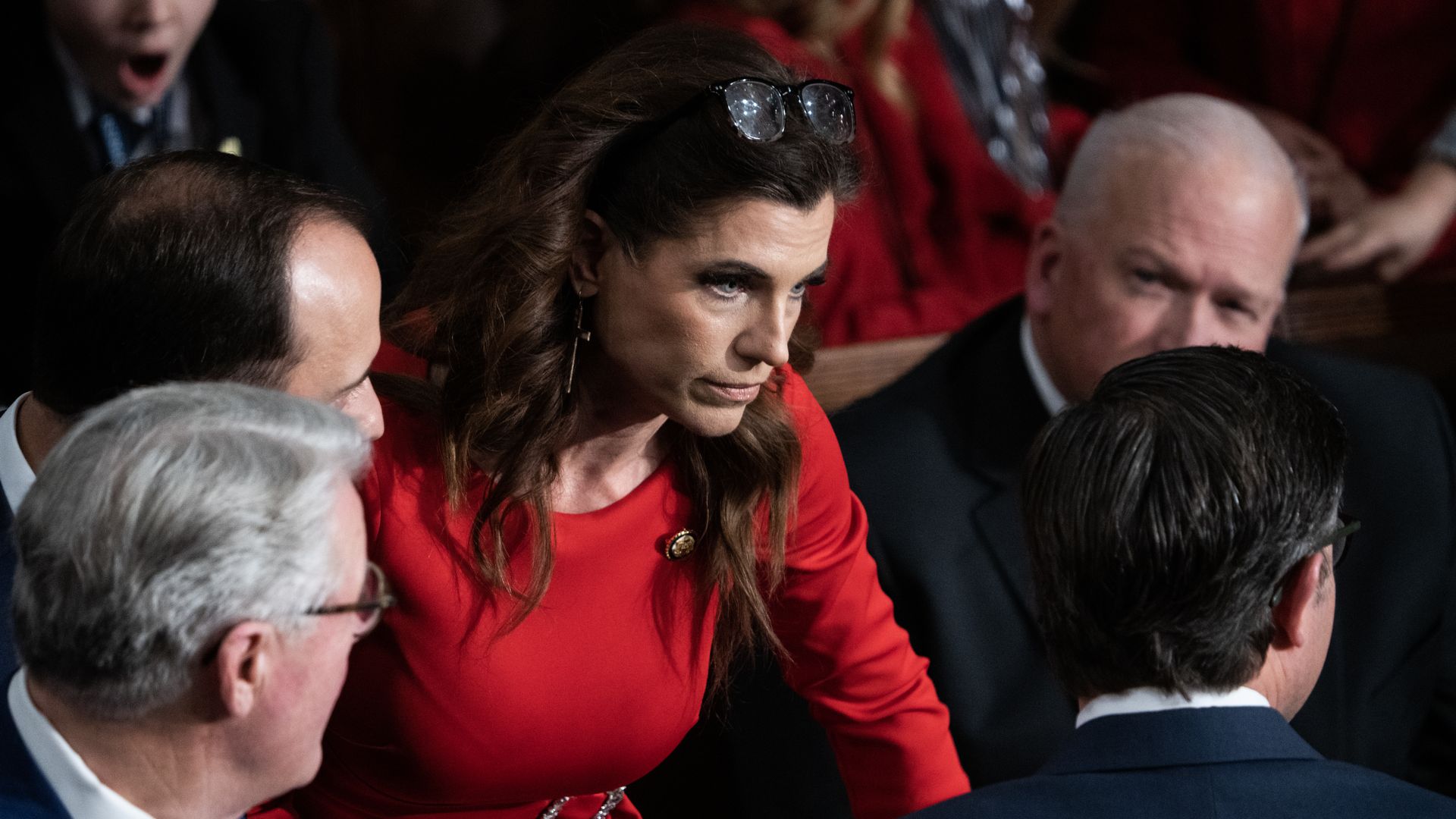 Rep. Nancy Mace, wearing a red dress and surrounded by colleagues in the House chamber.