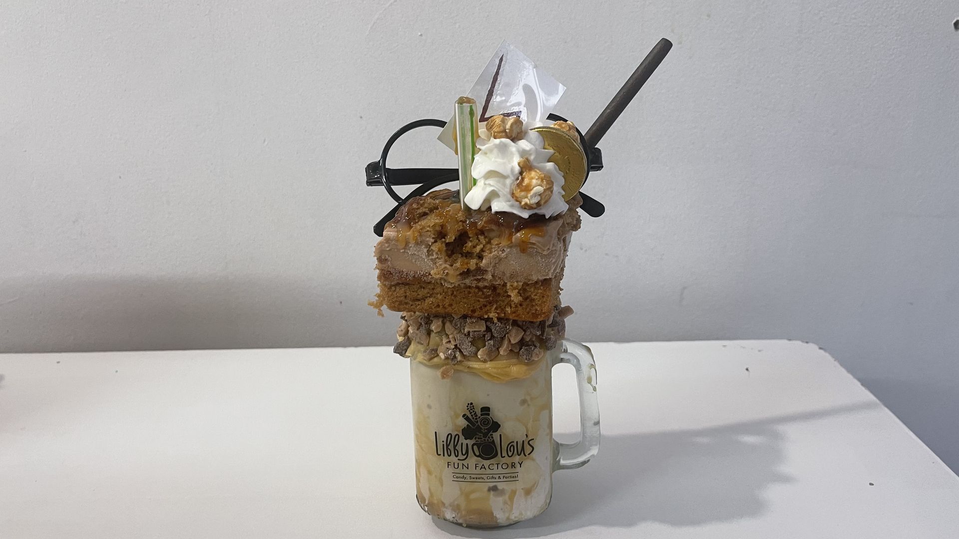 Harry Potter themed butterscotch milkshake topped with glasses, cake and a wand. 