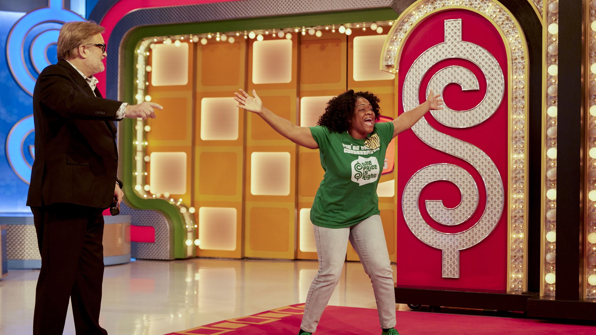 A woman with her arms outstretched, looking excited, on the stage of game show "The Price is Right."