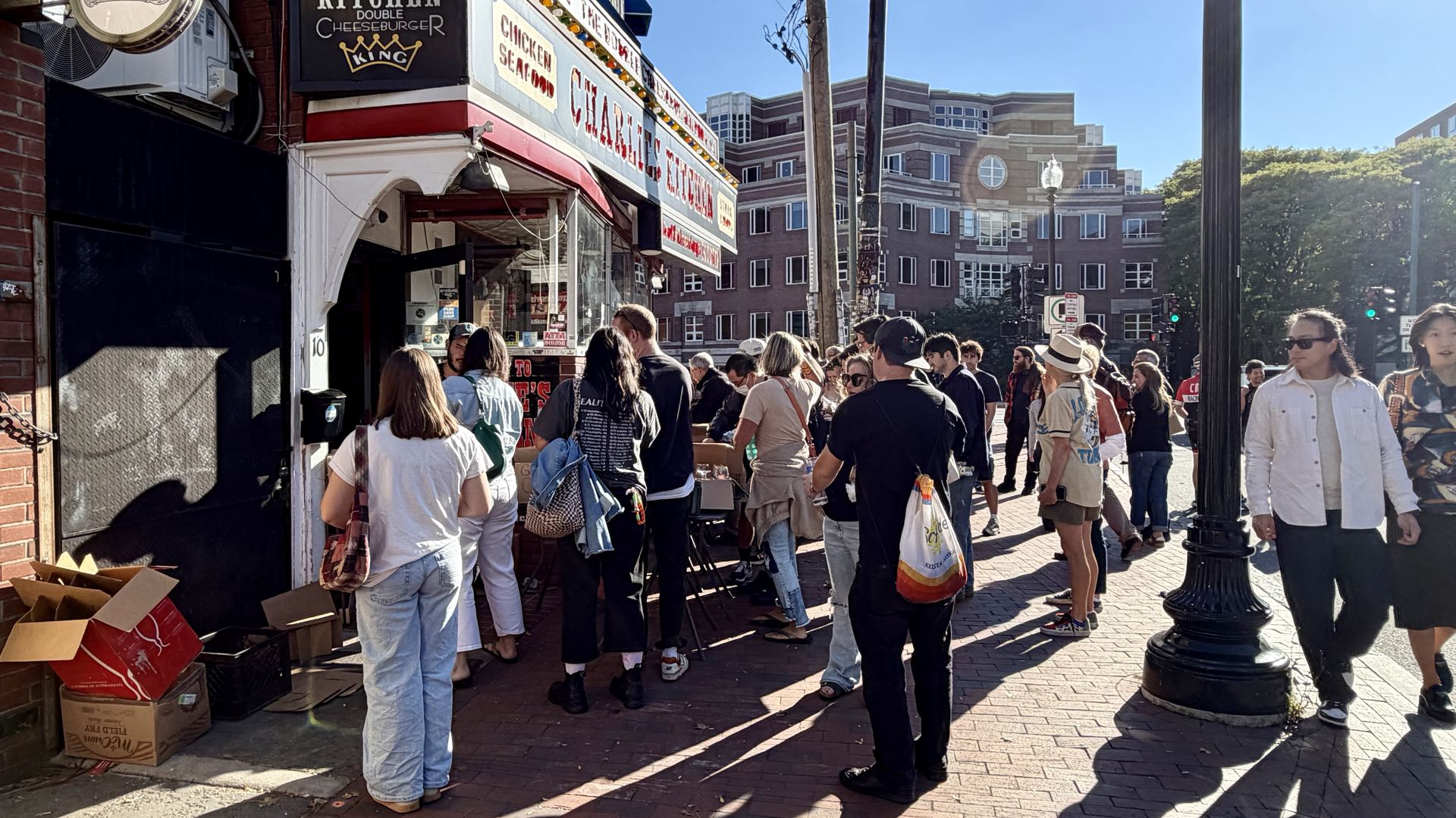 A crowd of people stand outside the shuttered Charlie's Kitchen on Eliot Street in Cambridge on Saturday, Oct. 3, 2026, as the owner holds a fire sale months after severe water damage.