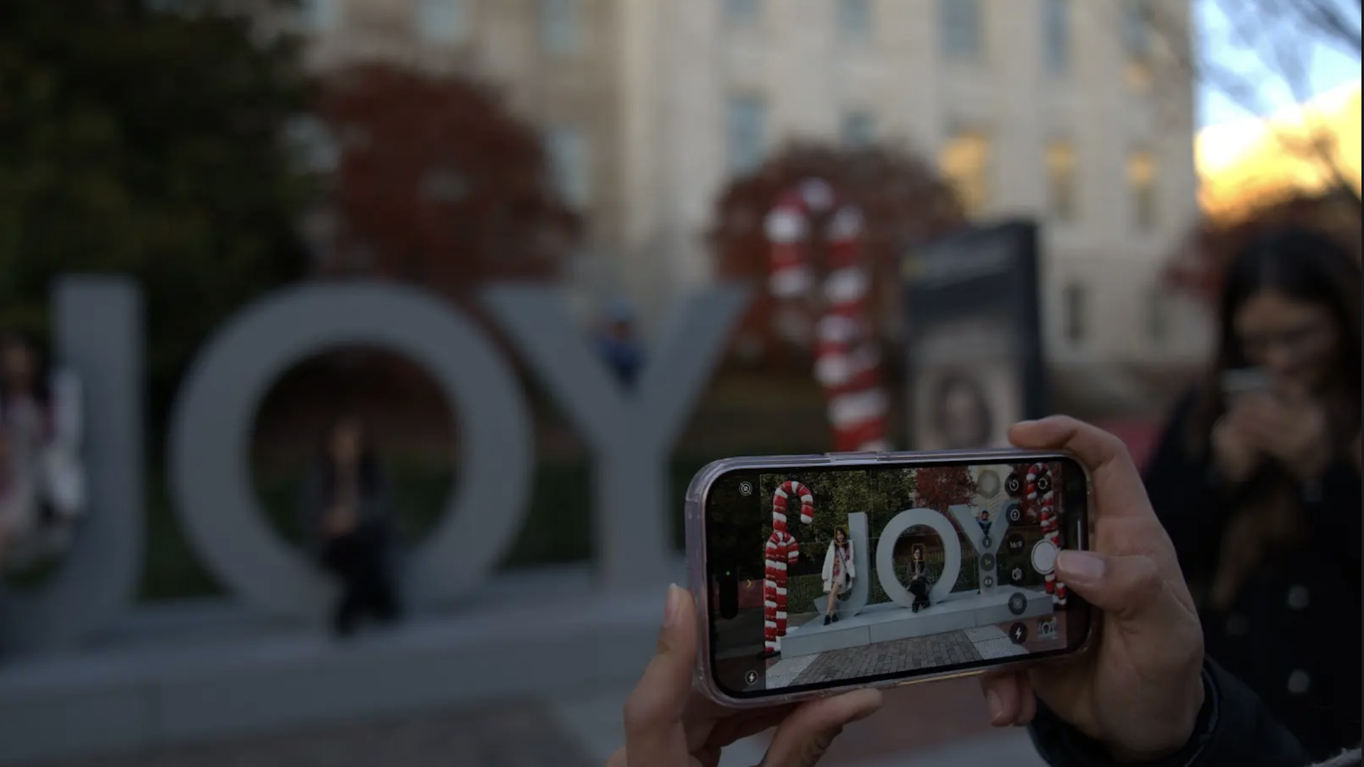 A phone screen showing a photo of holiday decorations that say "joy."