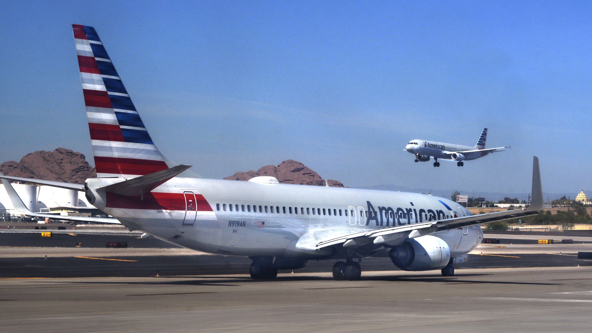 An American Airlines jet takes off as another taxis to its gate at Phoenix Sky Harbor Airport.