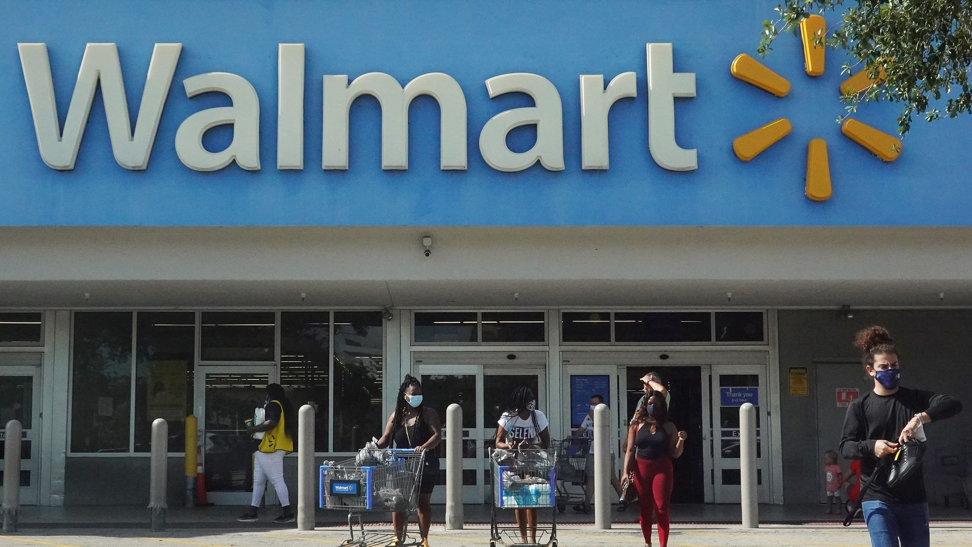 People wearing protective masks walk from a Walmart store on May 18, 2021 in Hallandale Beach, Florida.