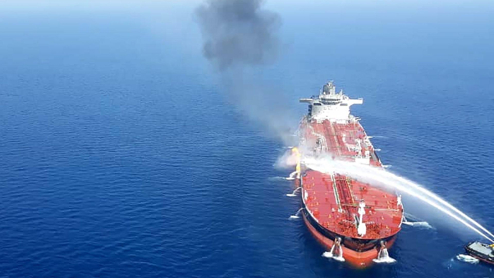 In this image, jets of water are shot onto a large oil tanker on the ocean.