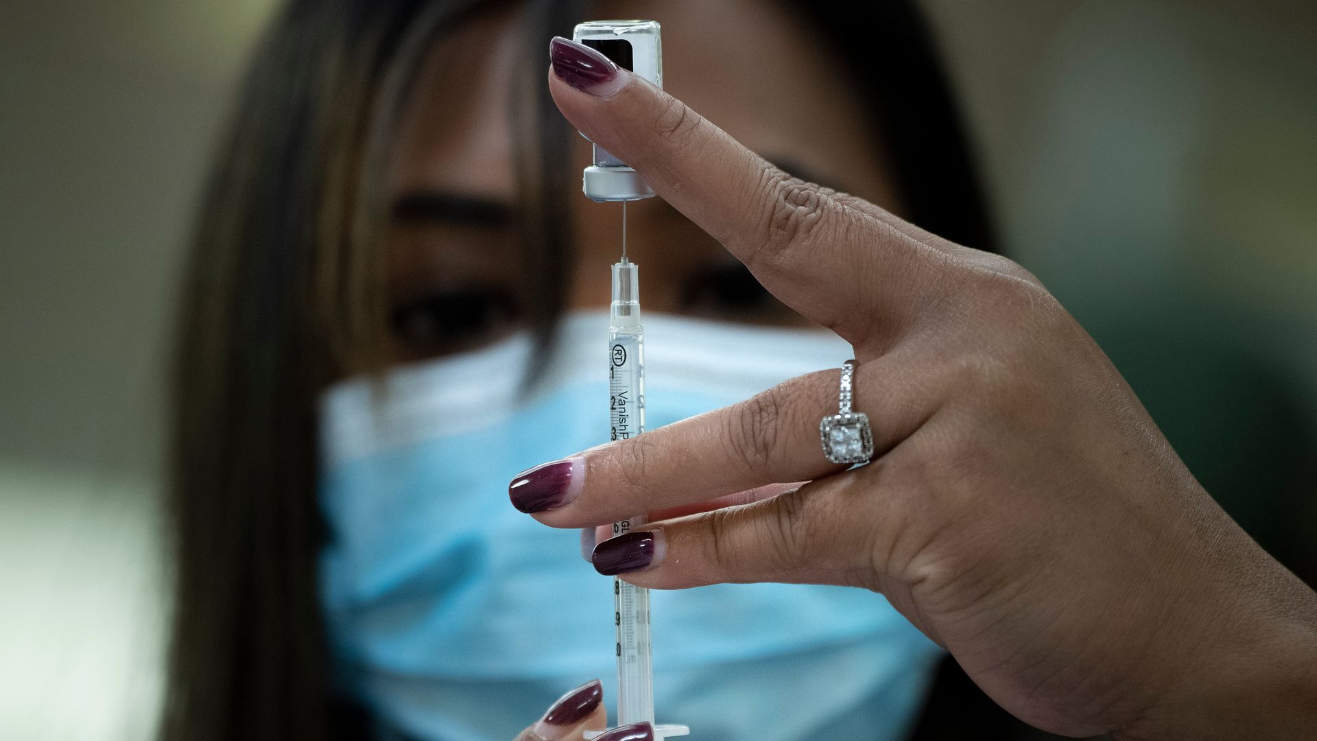 Photo of a masked person holding up a syringe