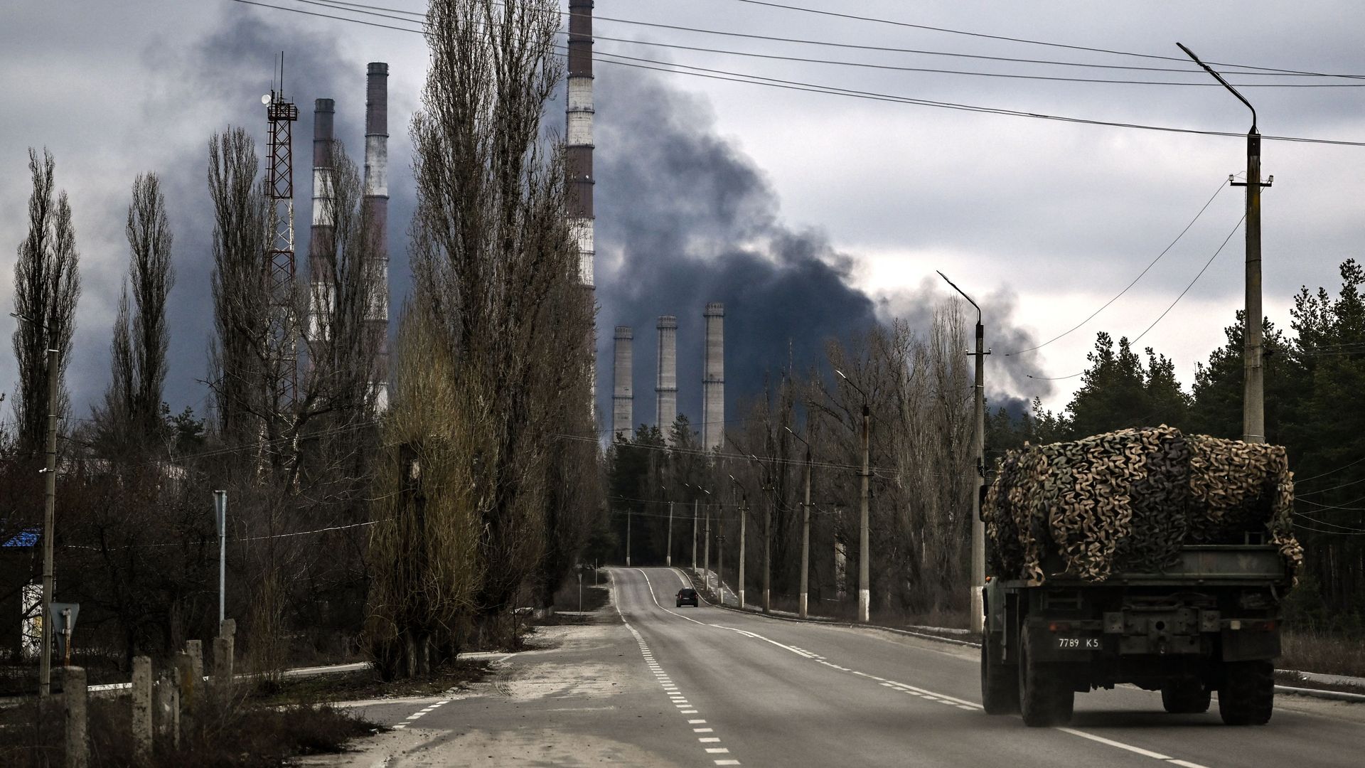 A military vehicle driving near the city of Shchastia on Feb. 22 with a smoke rises from a fire at a power plant.