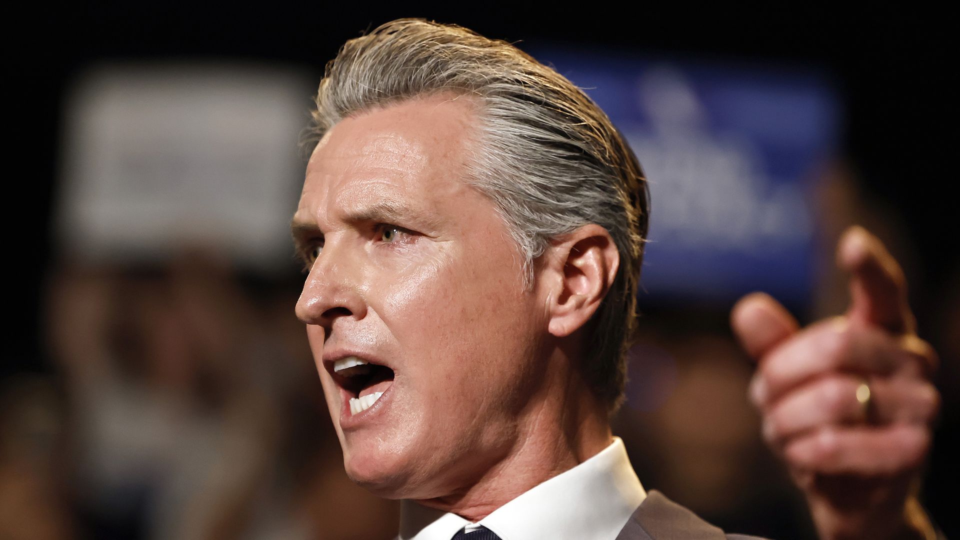 A close-up of Gavin Newsom turning to the side as he points and speaks at an event.