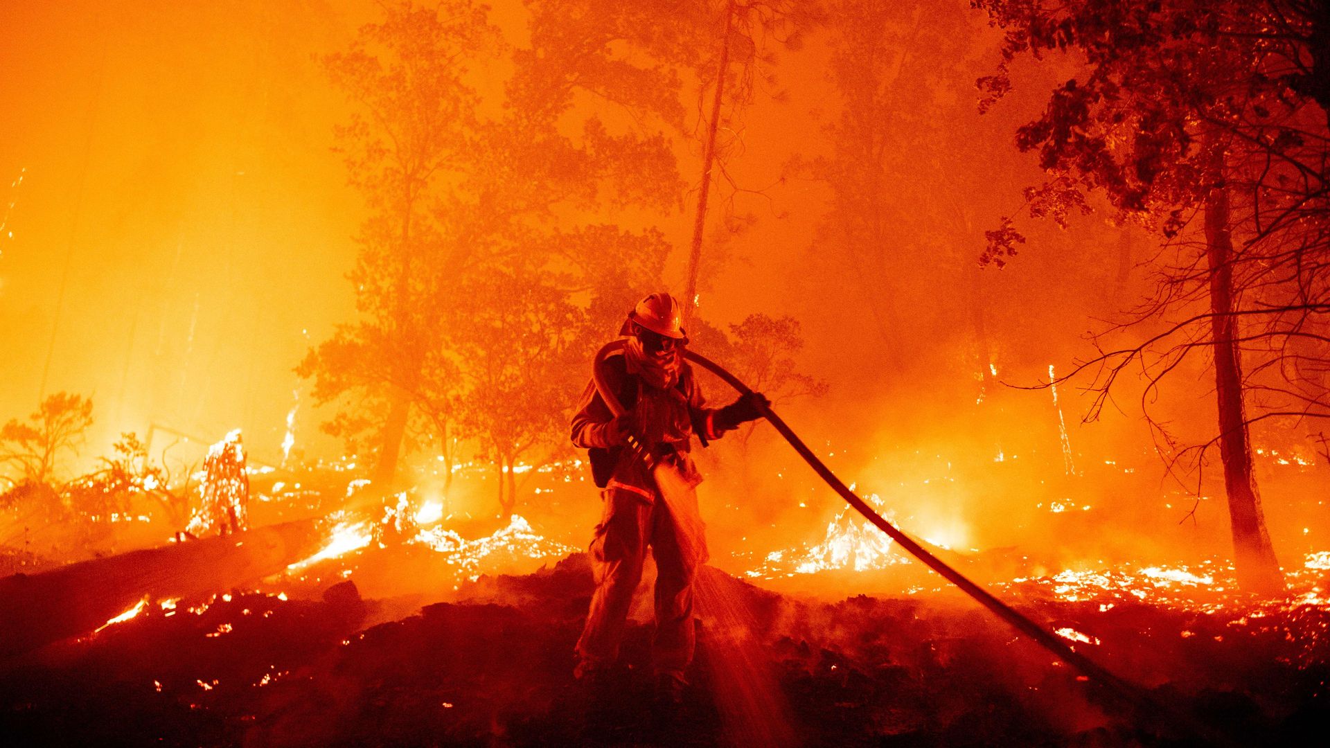 A firefighter douses flames as they push towards homes during the Creek fire in the Cascadel Woods area of unincorporated Madera County, California on September 7