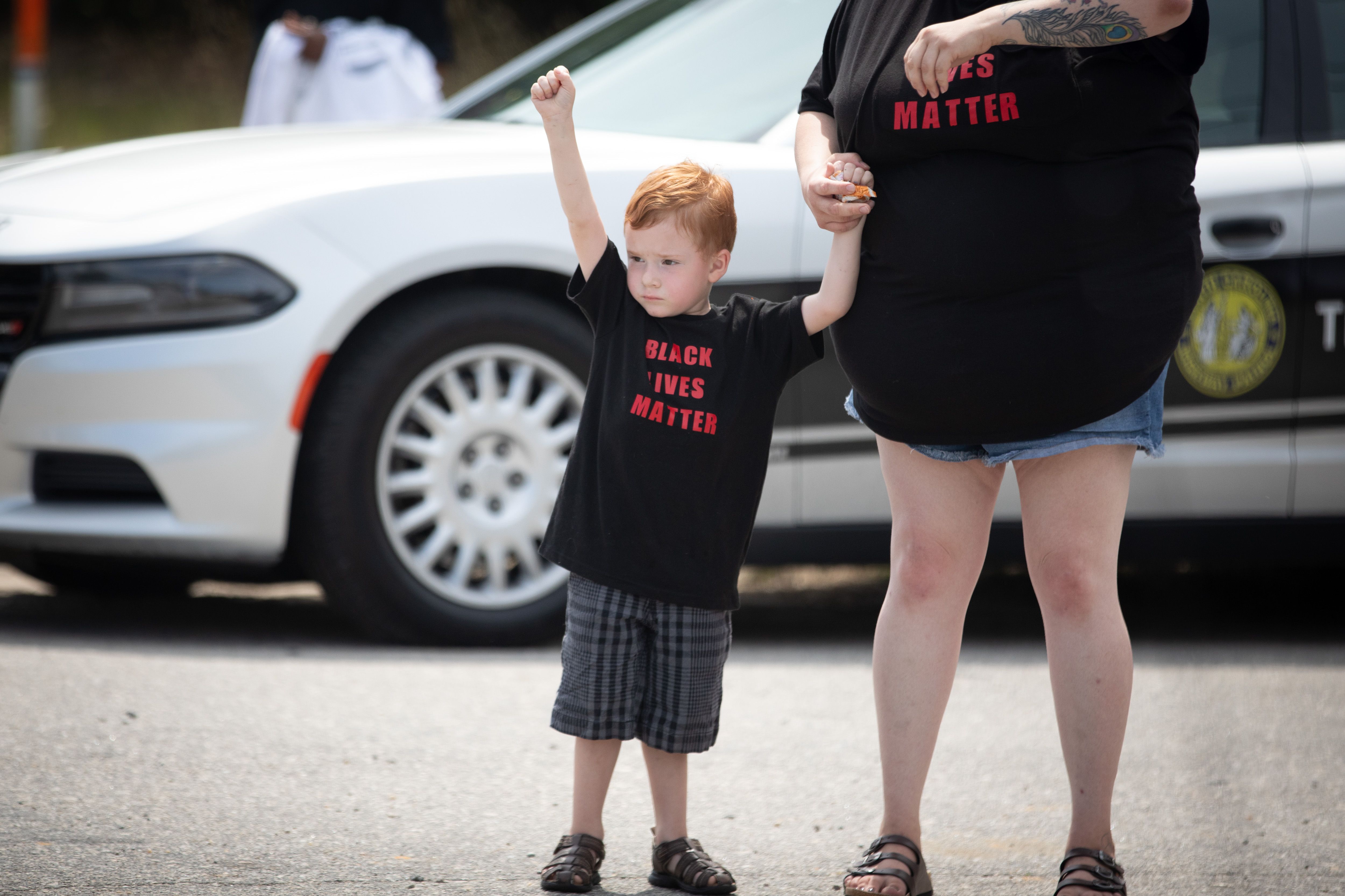 A boy raises a fist as a group of bikers arrive to pay their respects to George Floyd