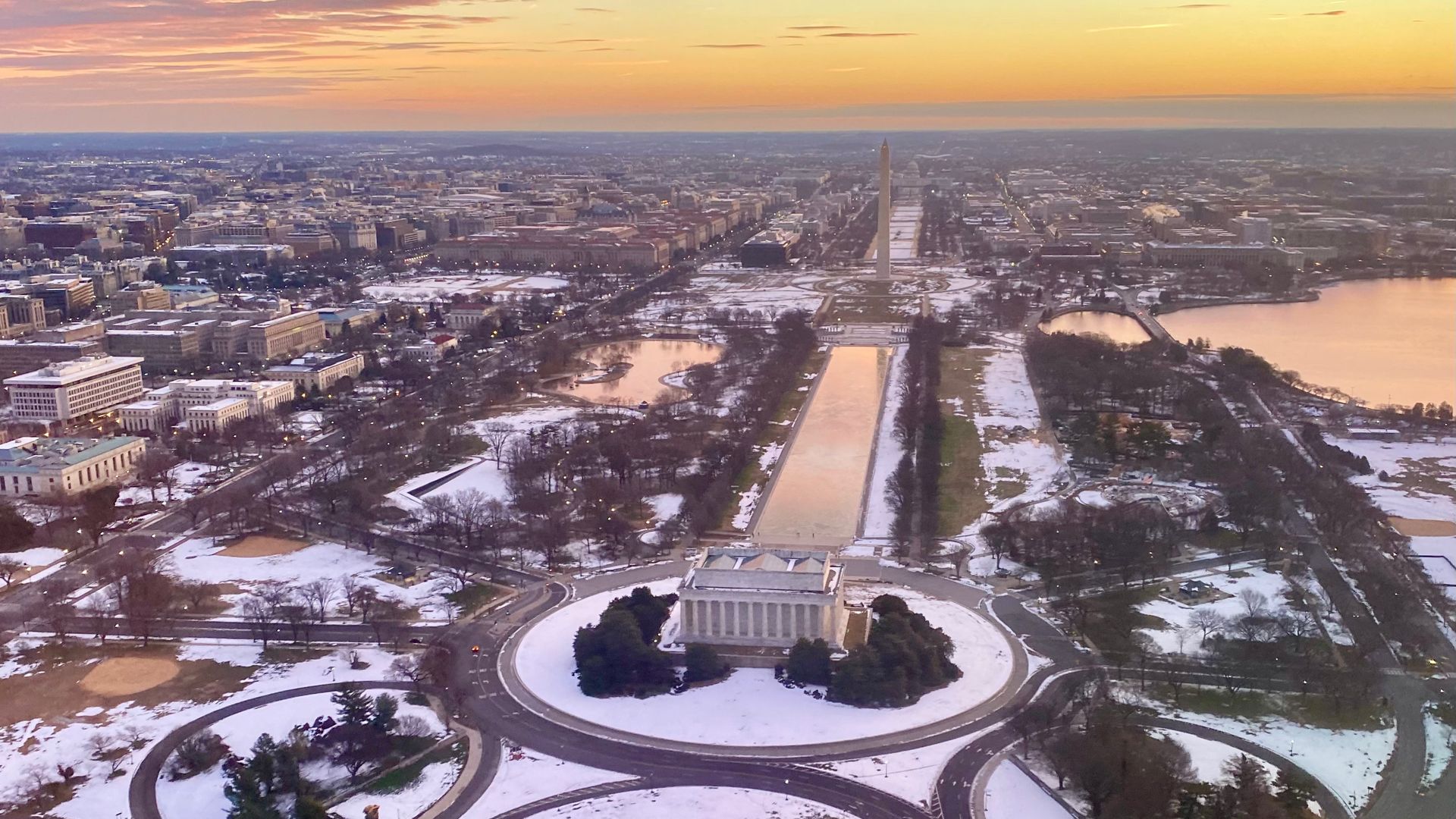 The sun is seen rising behind the Lincoln Memorial and National Mall.