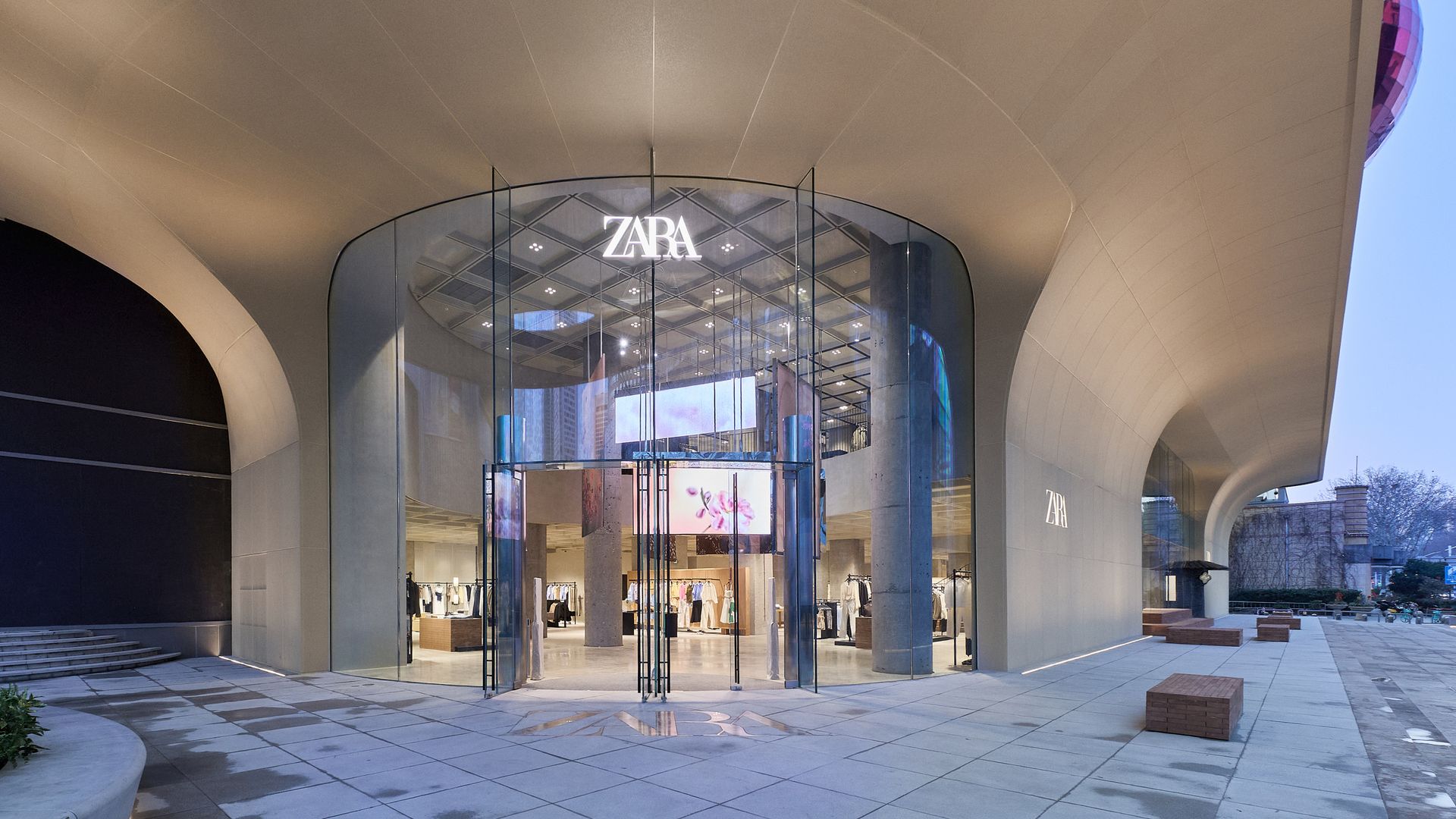 Photo of the entrance to a Zara flagship store in Nanjing, with clear glass and racks of clothing in the front