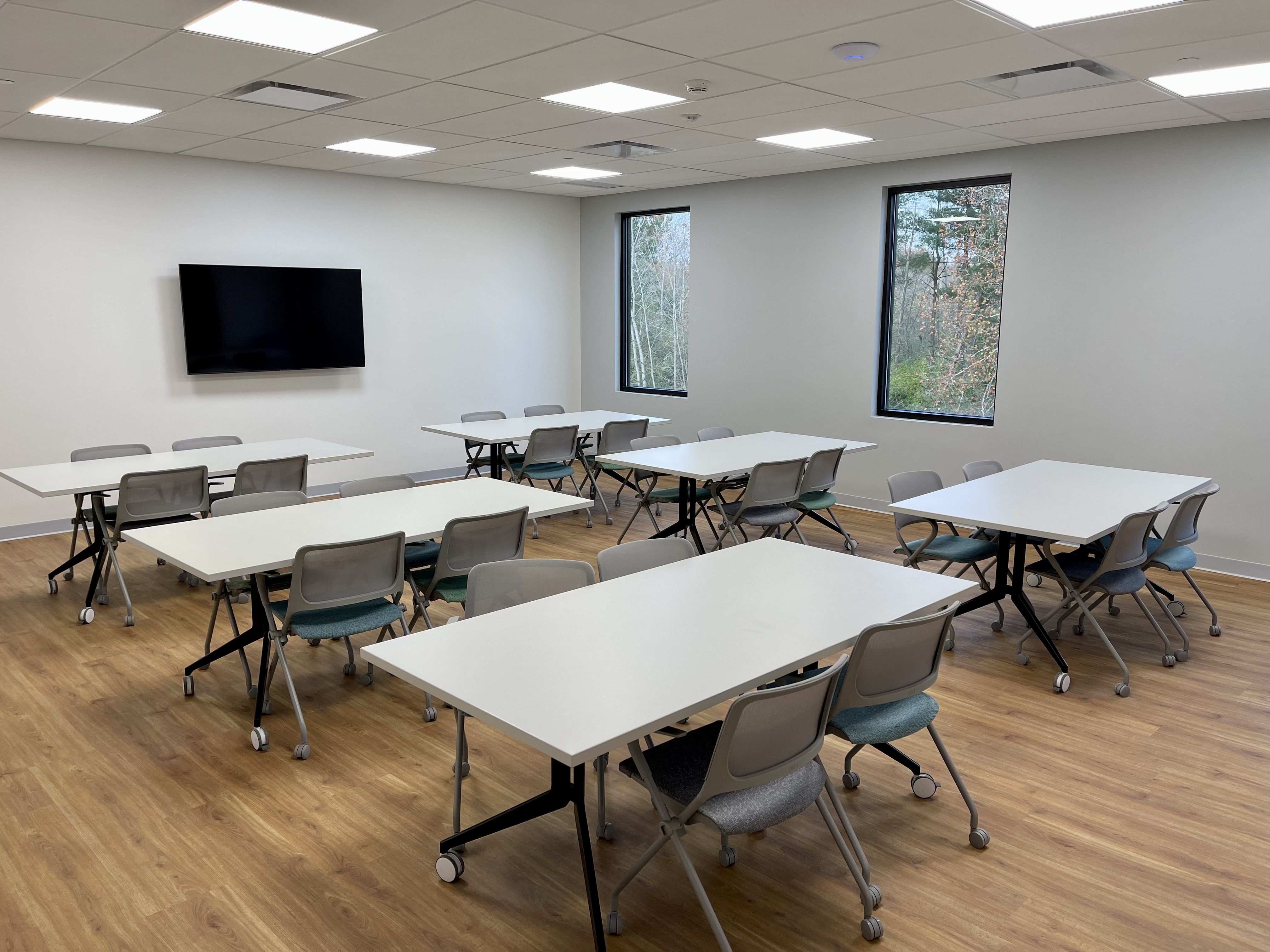 A small, flexible classroom space with tables and chairs on wheels and a TV