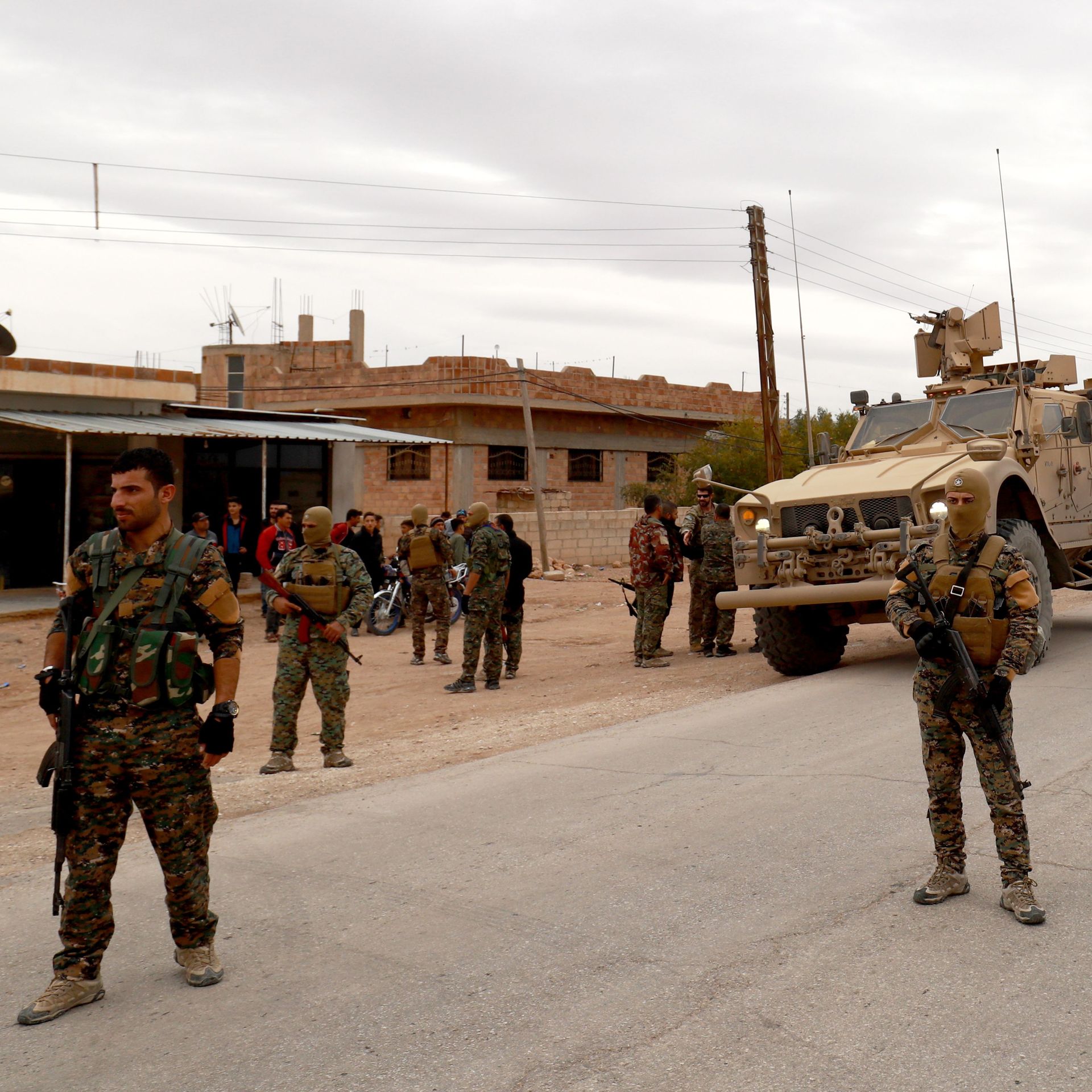 soldiers on foot patrolling a town, with tanks in the background