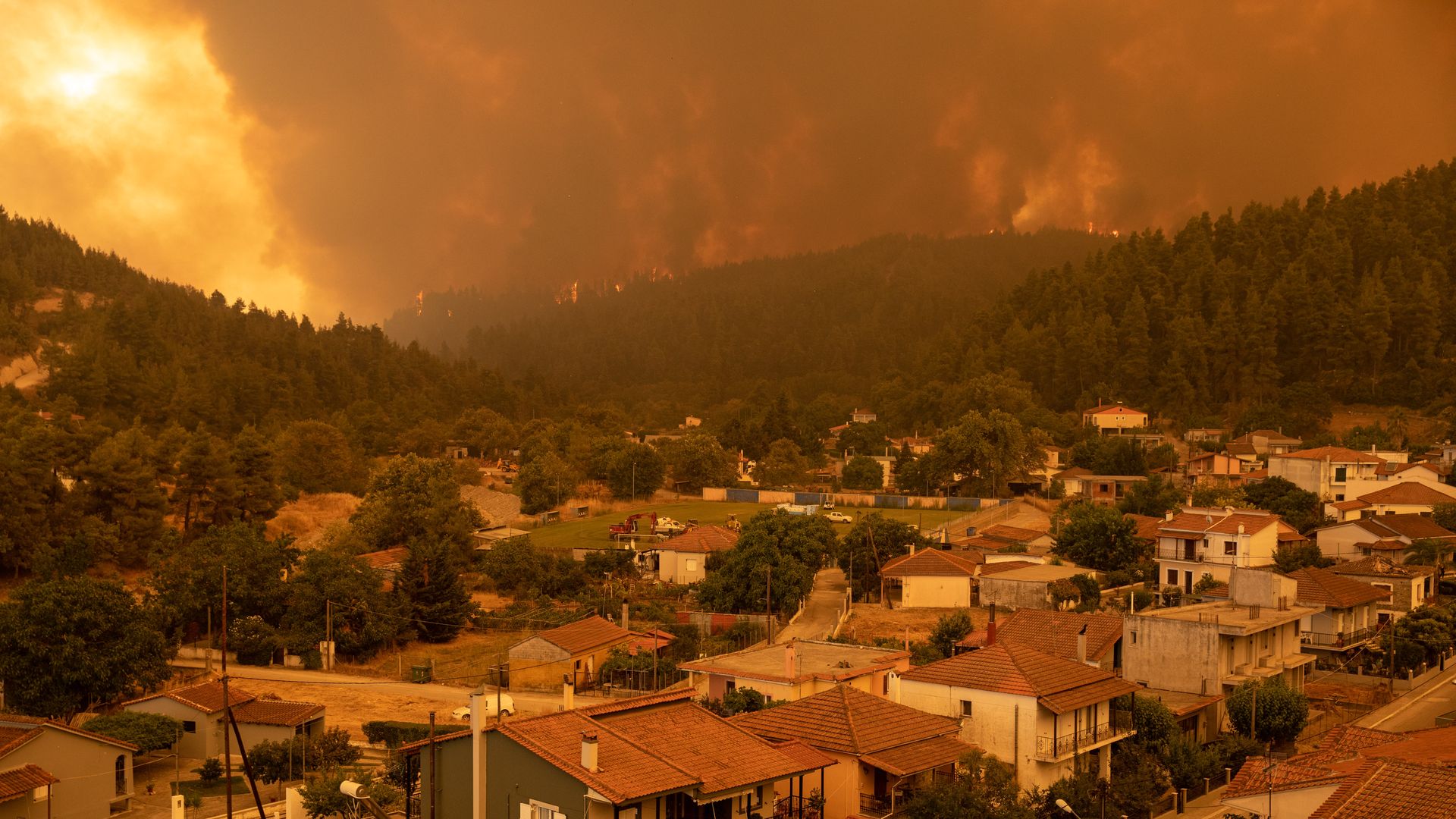 Billowing smoke and flames loom over a small town.