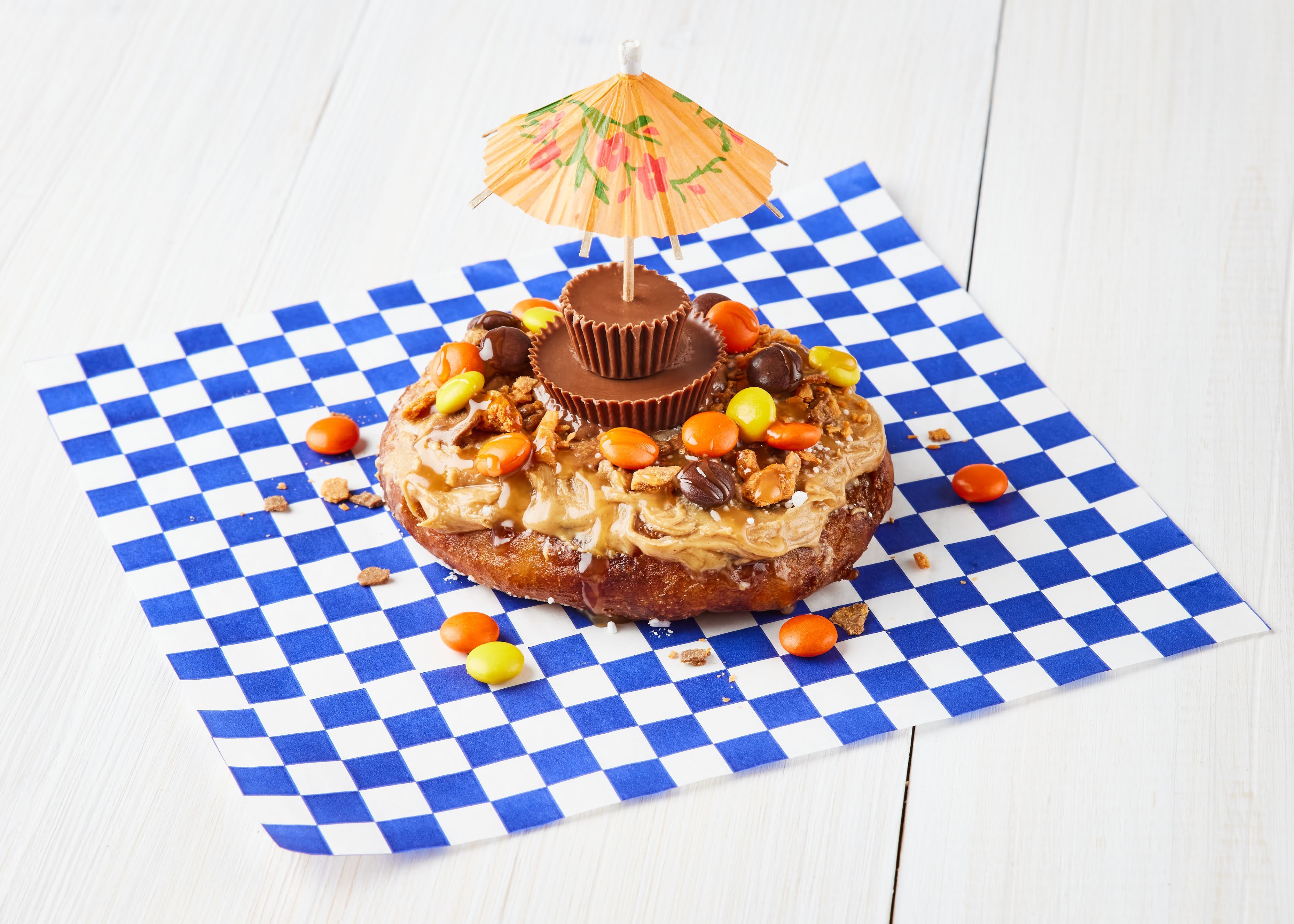 A cookie covered in peanut butter with a drink umbrella sticking out