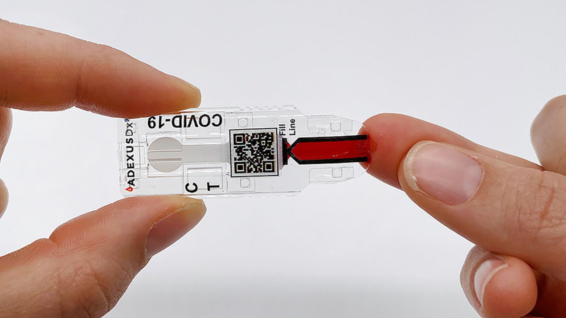 A hand holds a COVID test which pricks the finger of another hand