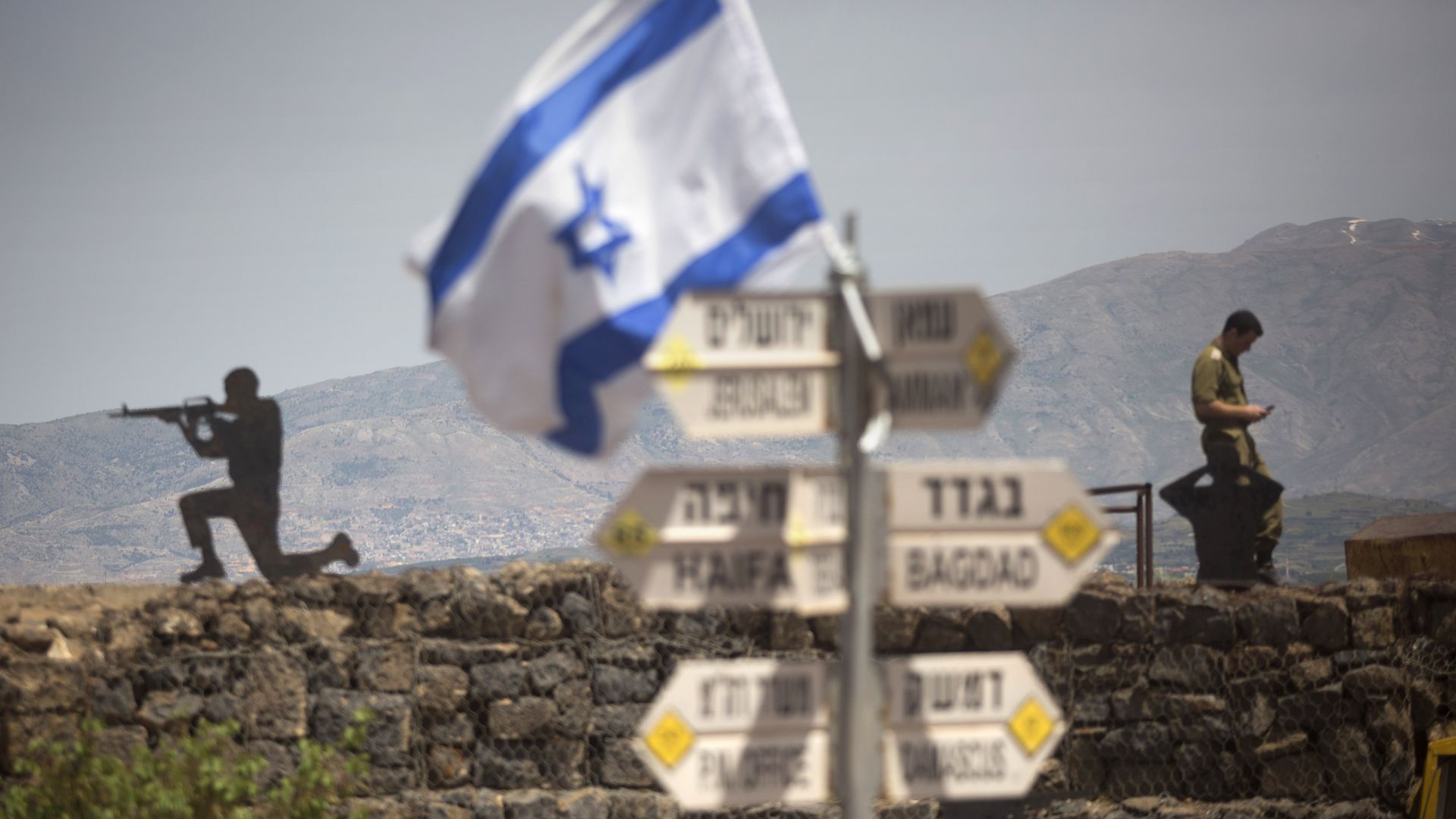 Israeli soldier is seen next to a signs pointing out distance to different cities on Mount Bental next to the Syrian border on May 10, 2018 in the Israeli-annexed Golan Heights.