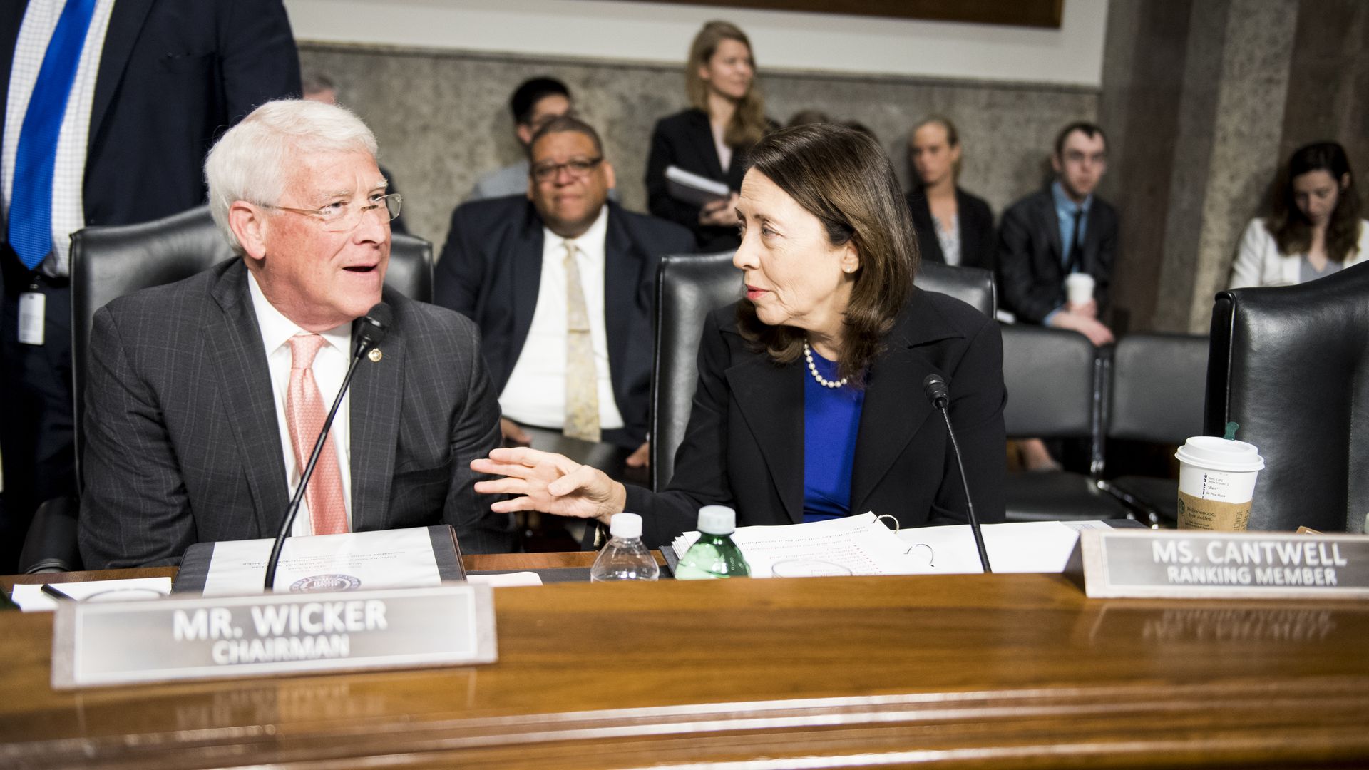 A man and woman in work attire speak to each other