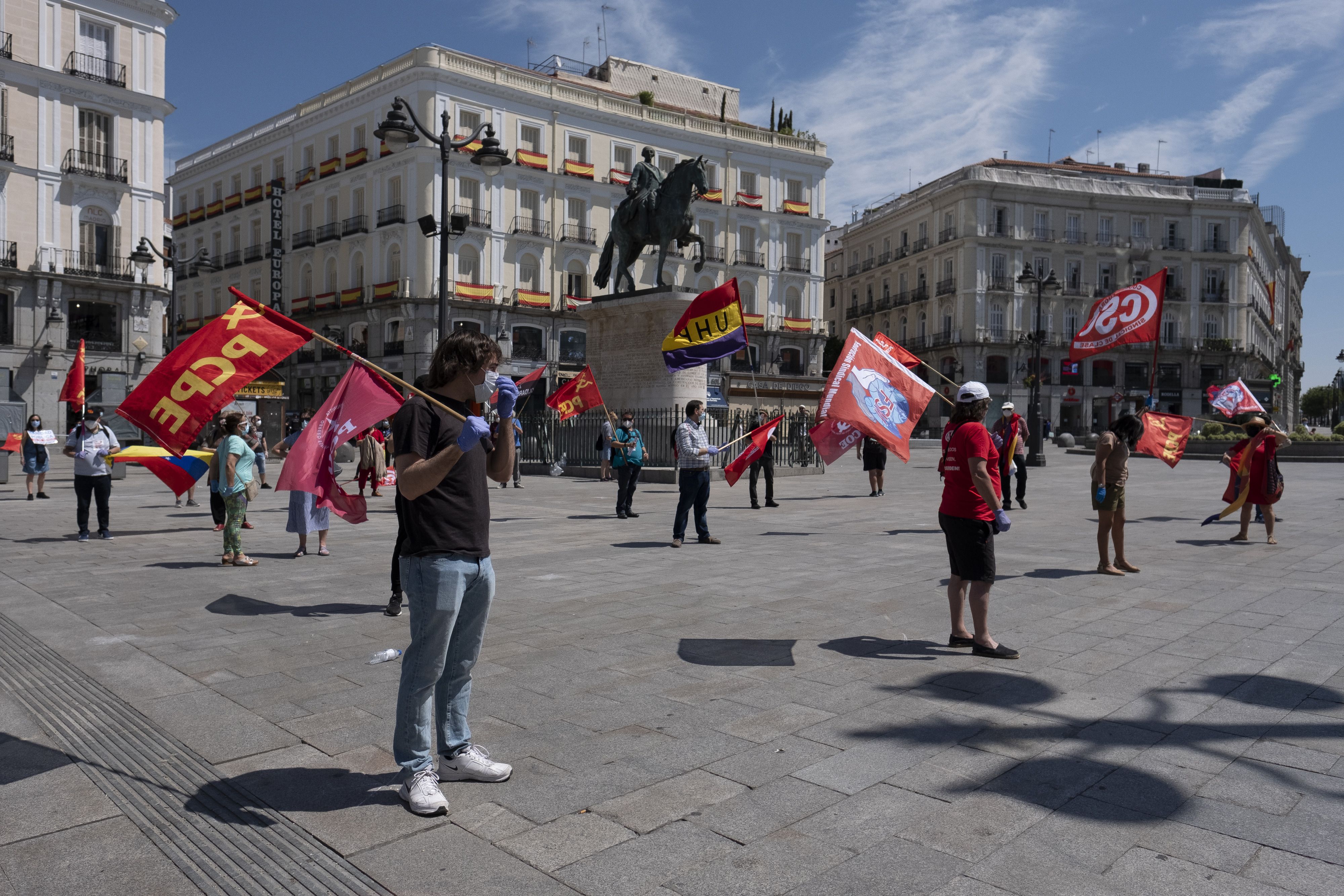 Protestors socially distance and hold flags in a square