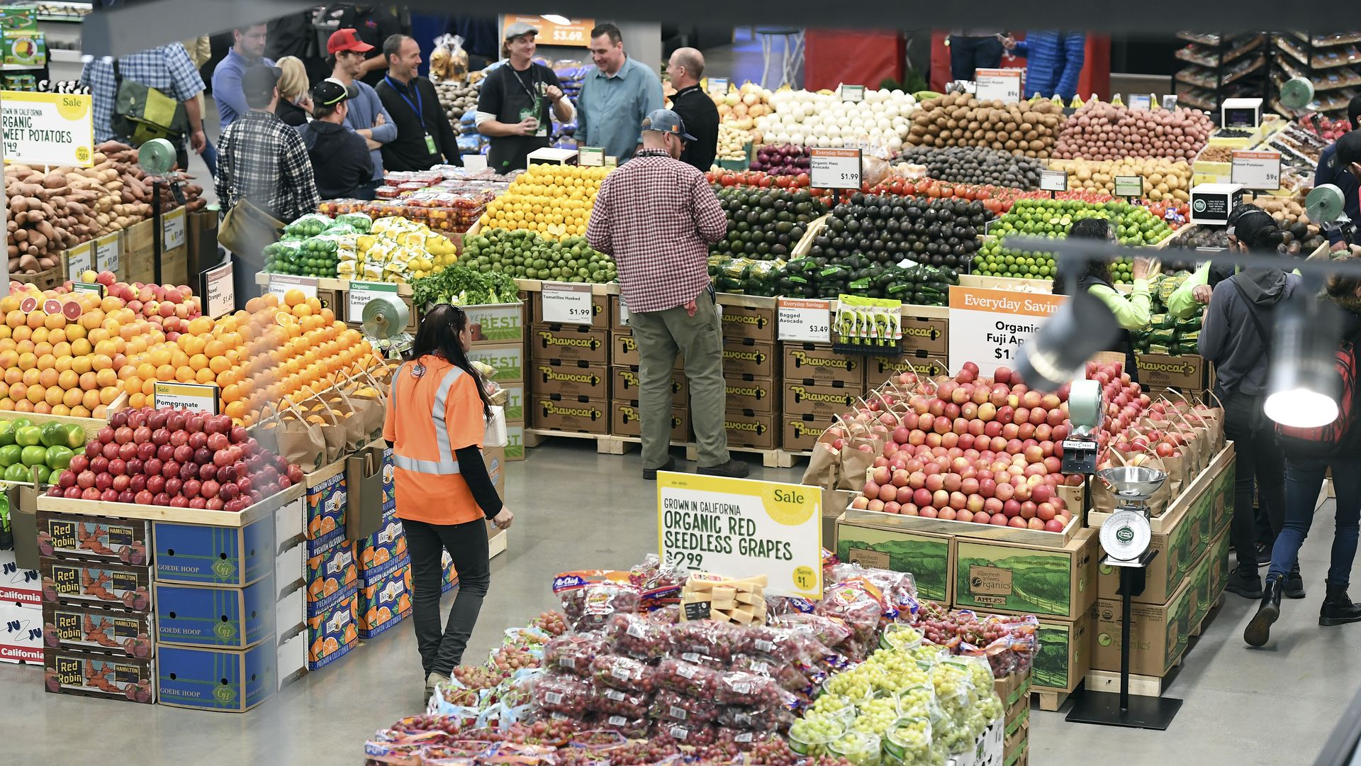 Shoppers and staff members at in a Whole Foods produce section