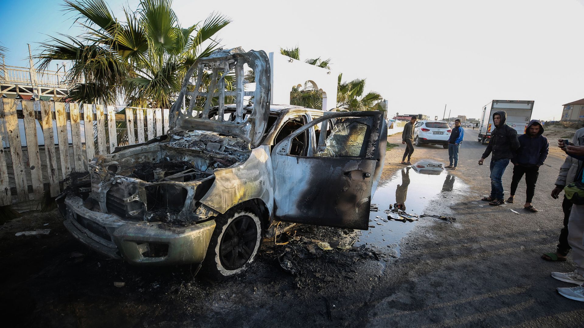 Palestinians are standing next to a destroyed vehicle in Deir Al-Balah, in the central Gaza Strip, on April 2, 2024, where employees from the World Central Kitchen were killed in an Israeli airstrike.