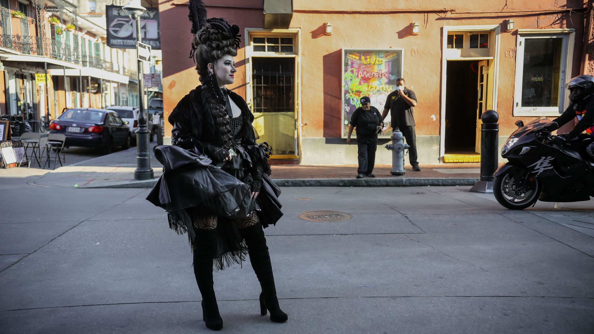 A woman dressed in an all-black costume stands on Bourbon Street.