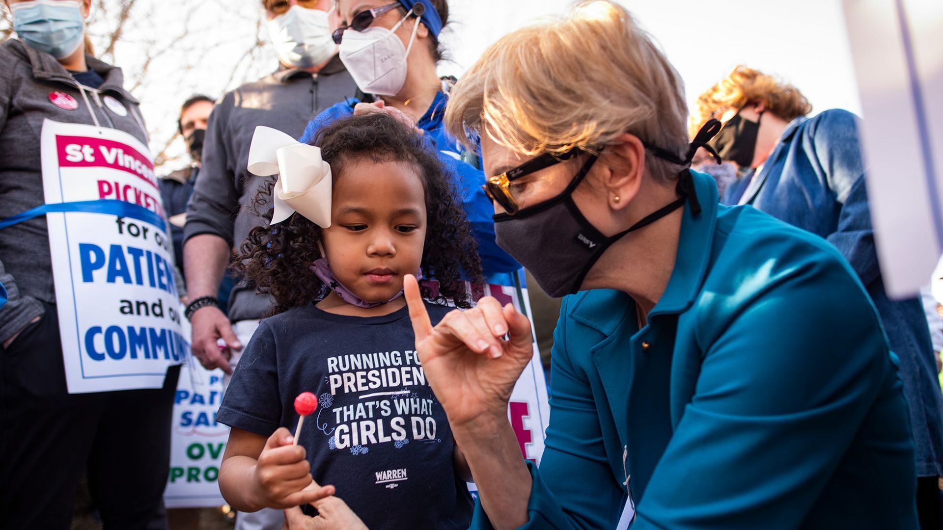 Picture of Elizabeth Warren giving a pinky promise to a little girl.