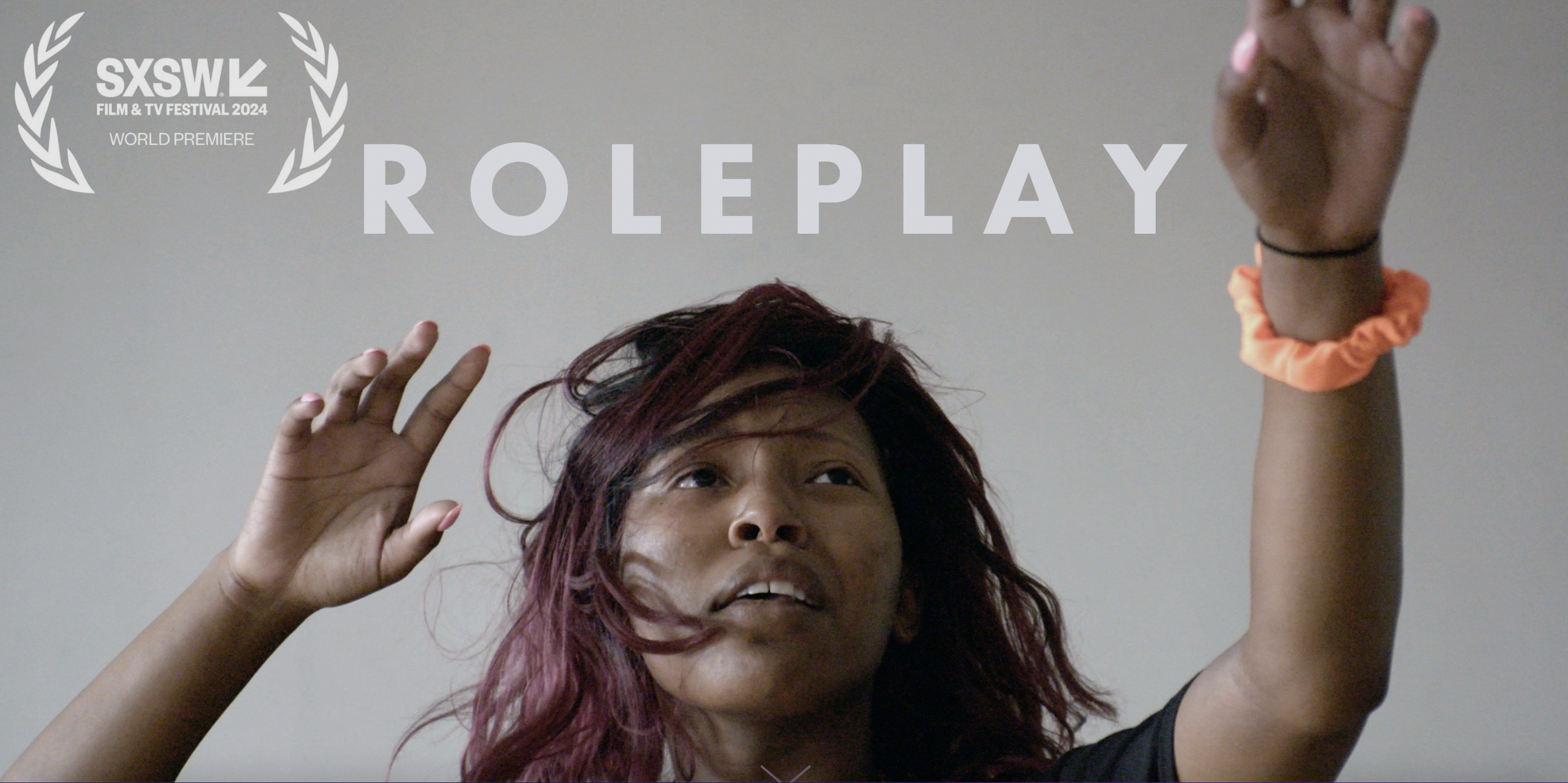 Image shows a screenshot from the "Roleplay" film a woman with her hands in the air.