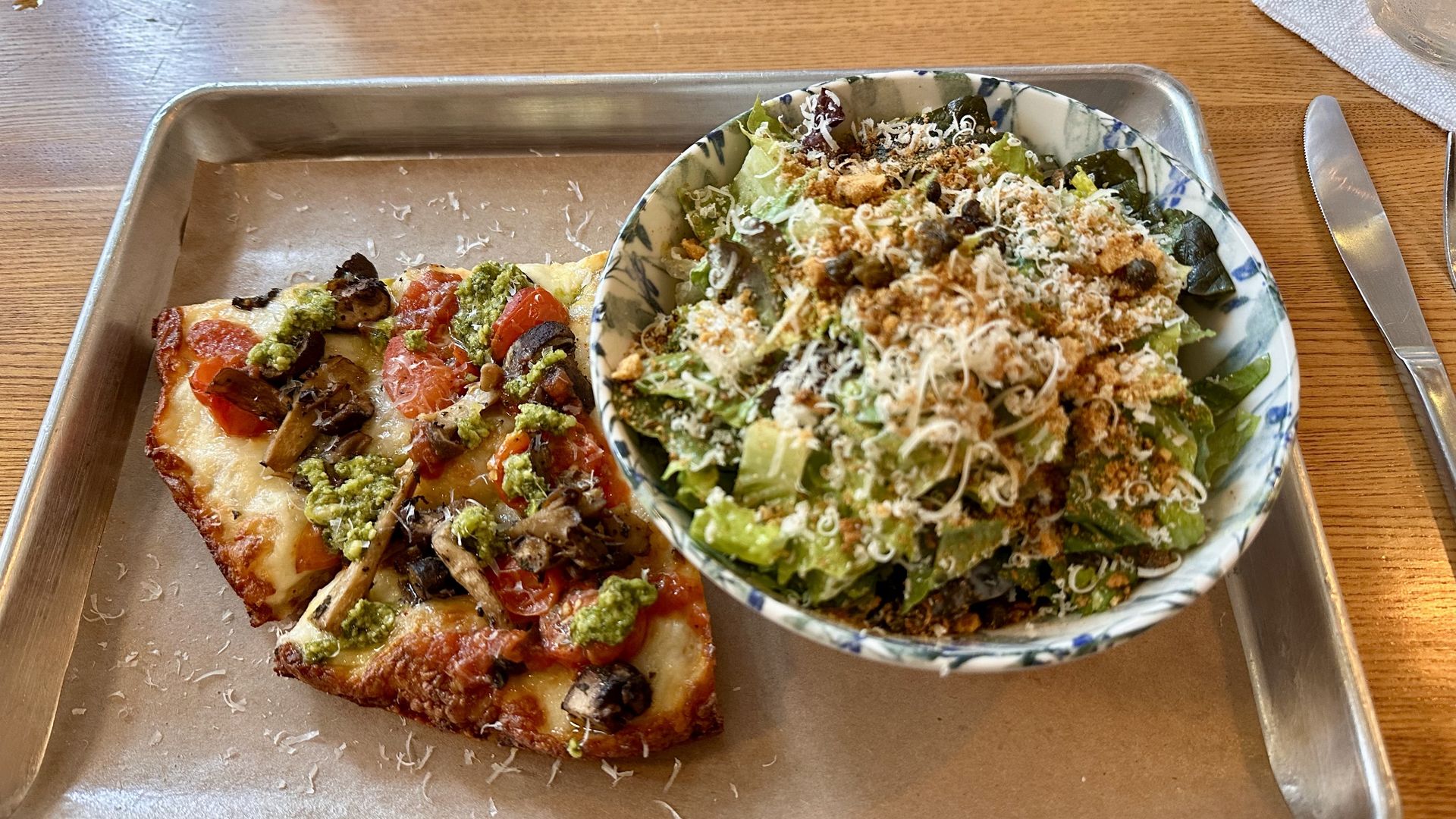 Two slices of pizza and a bowl of salad on a tray
