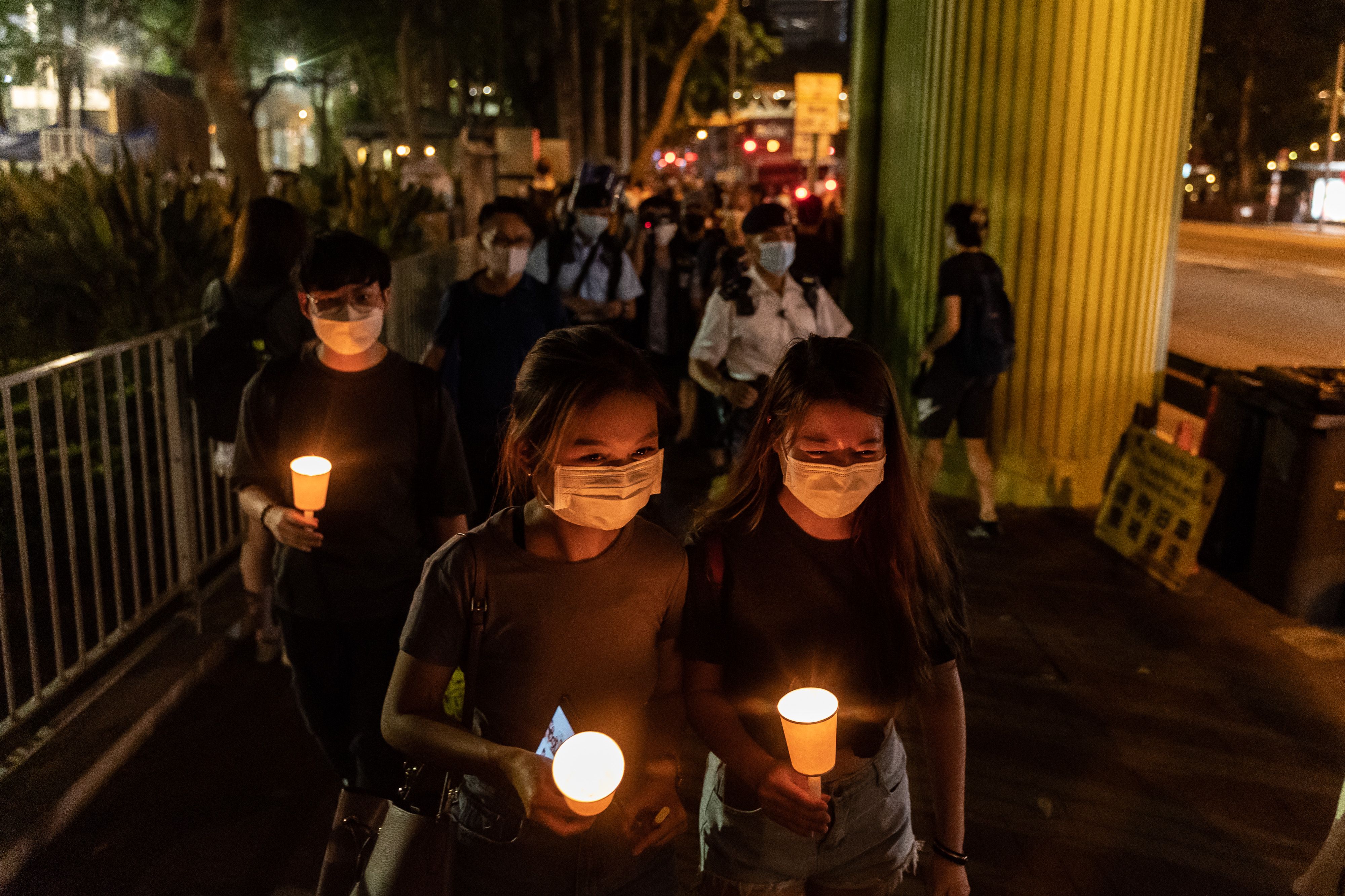 People hold candles as they walk near the Victoria Park in Hong Kong. 