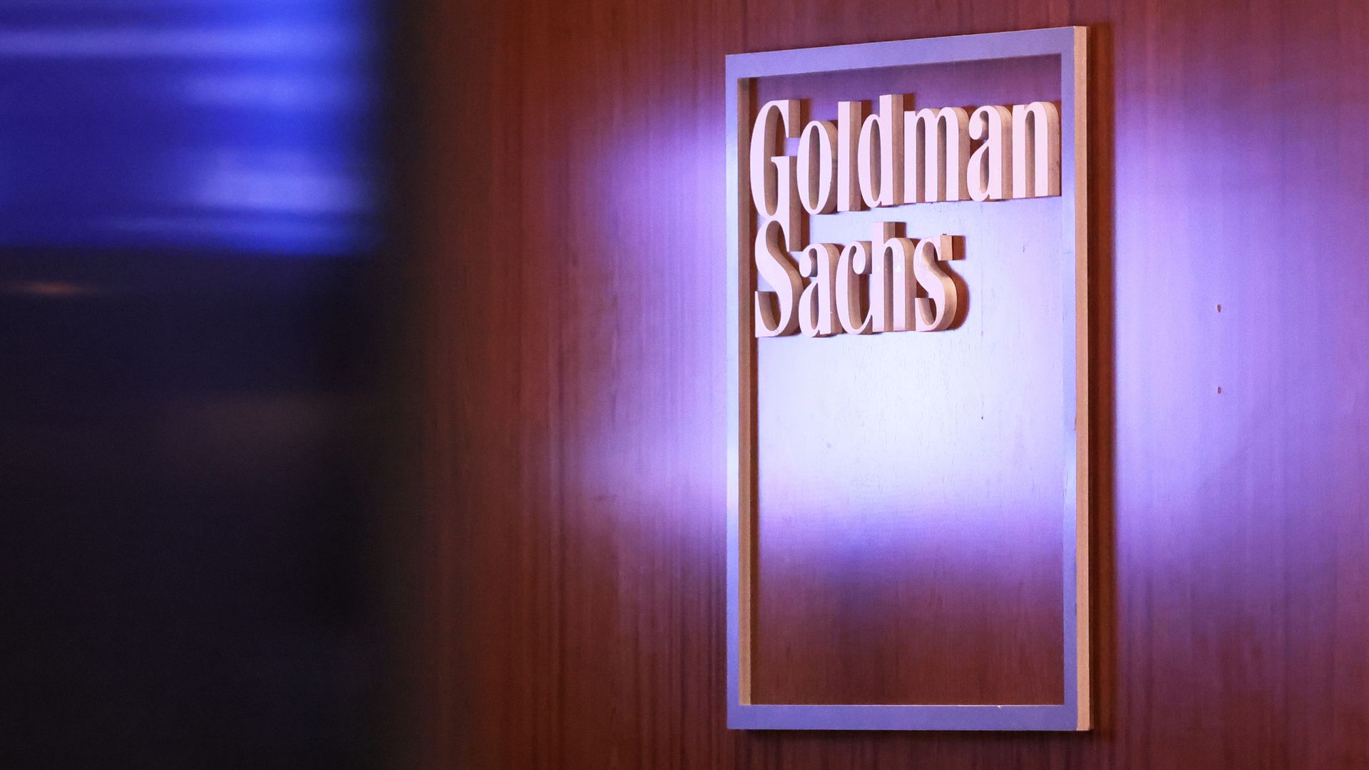The logo of Goldman Sachs in white letters against a wooden wall
