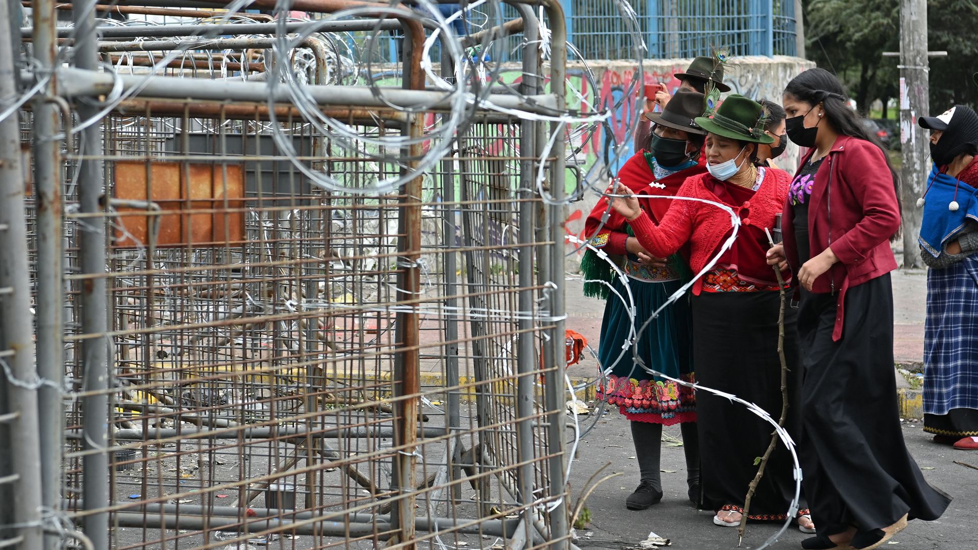 Indigenous Ecuadorian women stand outside barbed wire