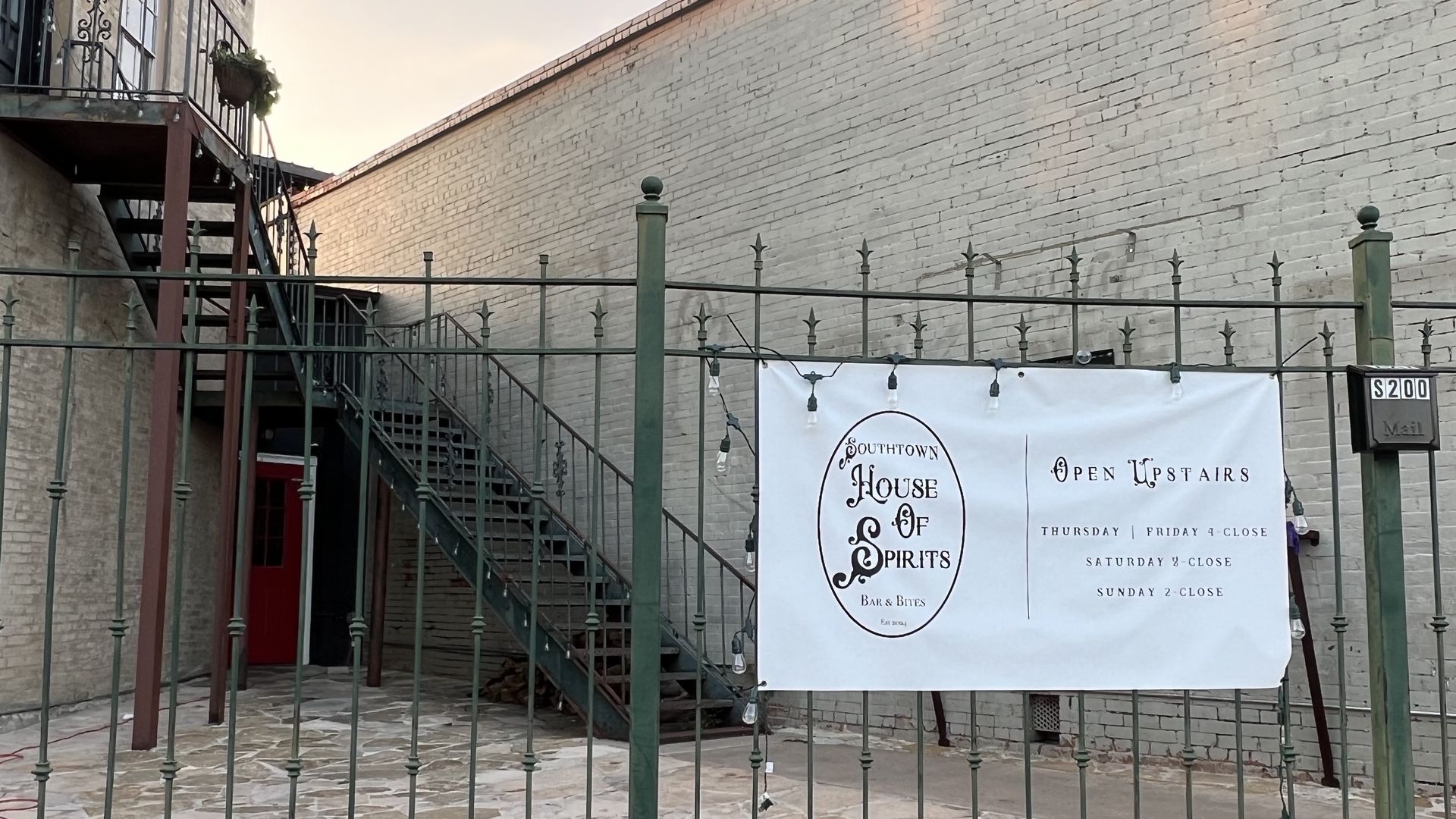A vinyl sign for Southtown House of Spirits hangs from a metal gate.