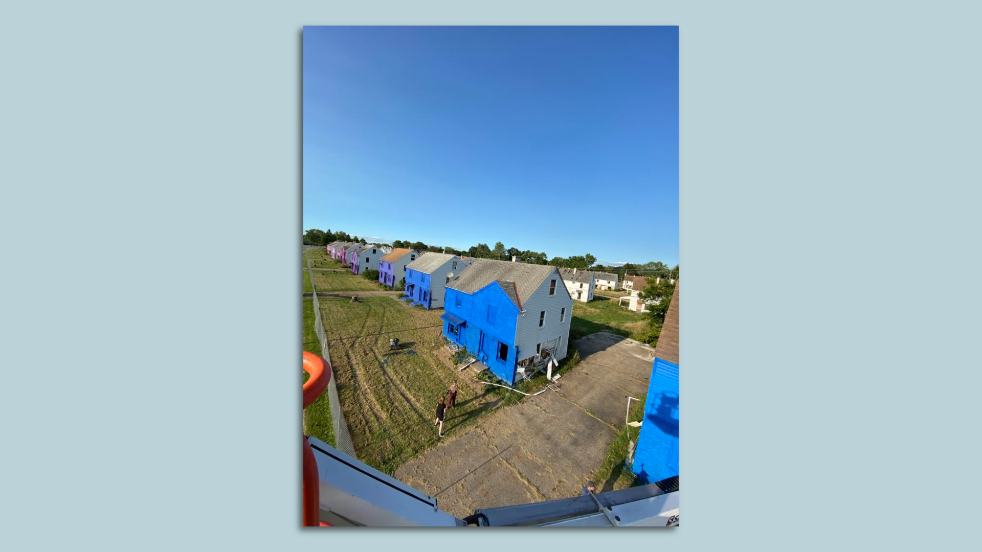 A birds-eye view of a row of painted houses in a blighted neighborhood. 
