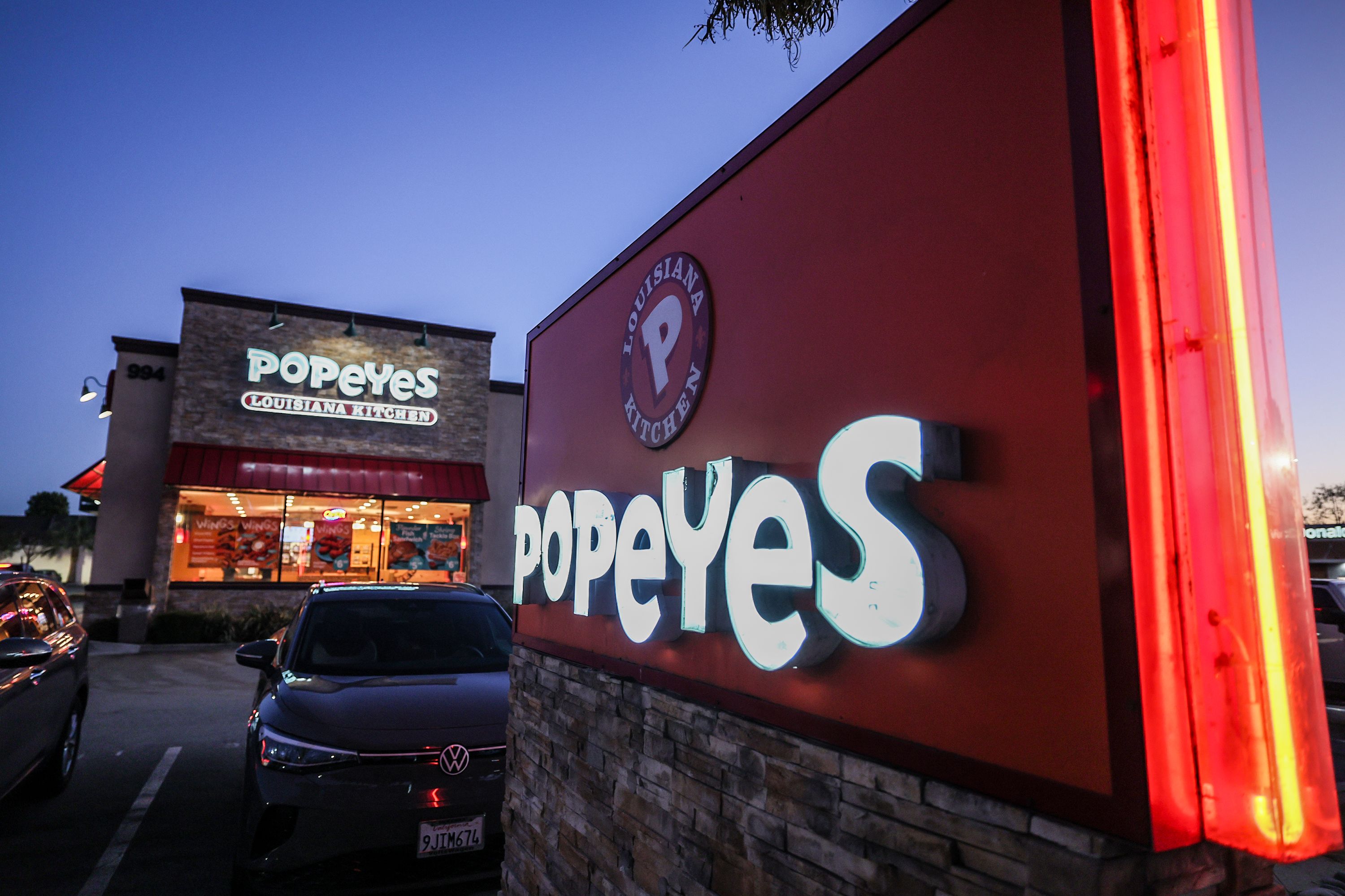 A lit up Popeyes storefront at night.