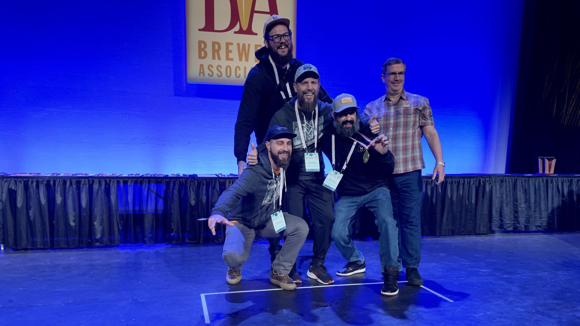 Photo of guys posing on stage accepting an award. 