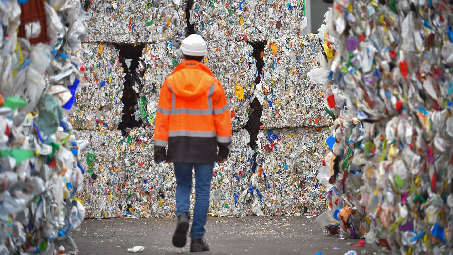An employee walks through plastic wastes waiting to be recycled at a sorting center