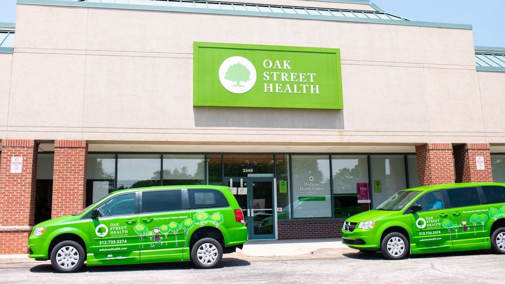 Two Oak Street Health green vans in front of an Oak Street Health clinic.