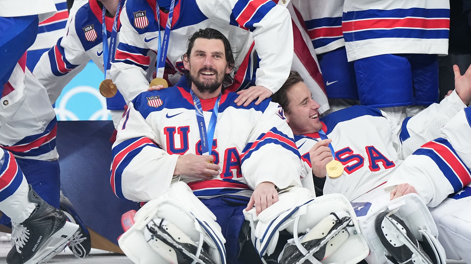Hellebuyck and other Team USA hockey players laying on the ground with gold medals