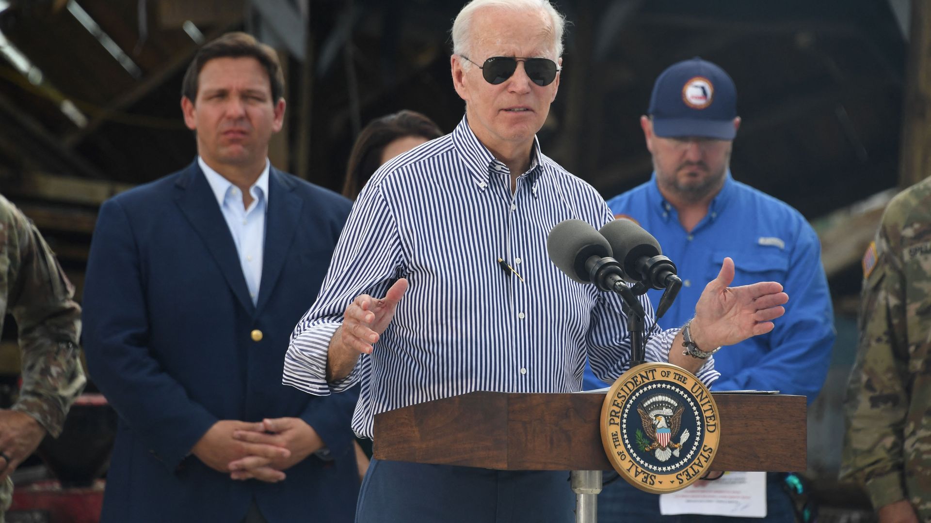 US President Joe Biden speaks in a neighborhood impacted by Hurricane Ian at Fishermans Pass in Fort Myers, Florida, on October 5, 2022 as Florida Governor Ron DeSantis looks on.