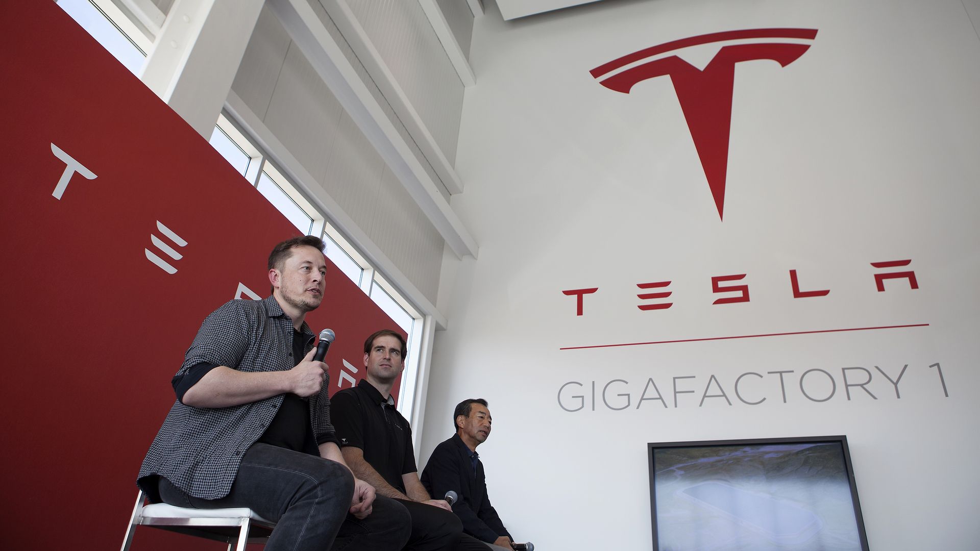 Three men answer questions while sitting on stools