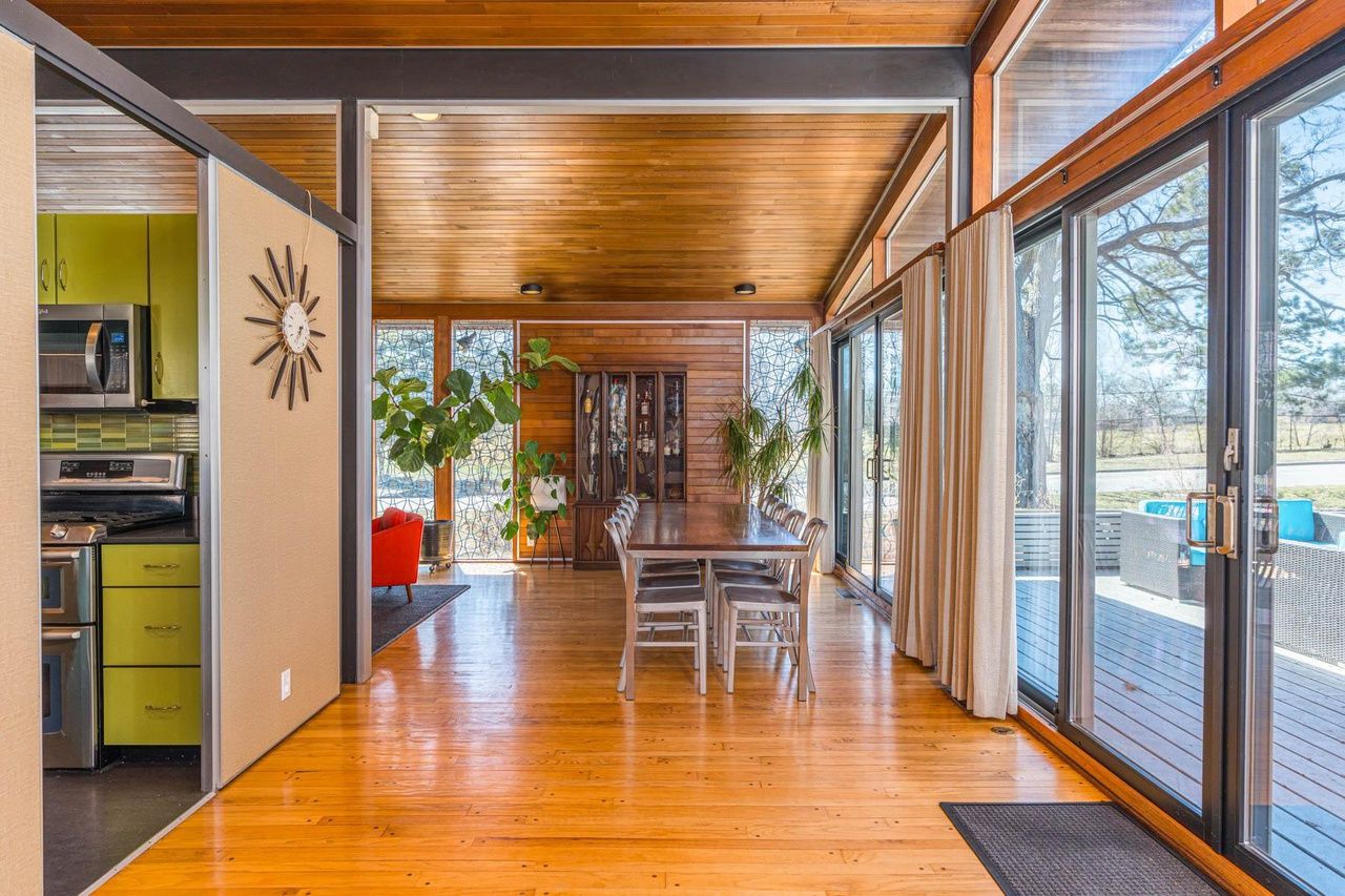 A mid-century modern style home with wooden ceilings and green cabinets.