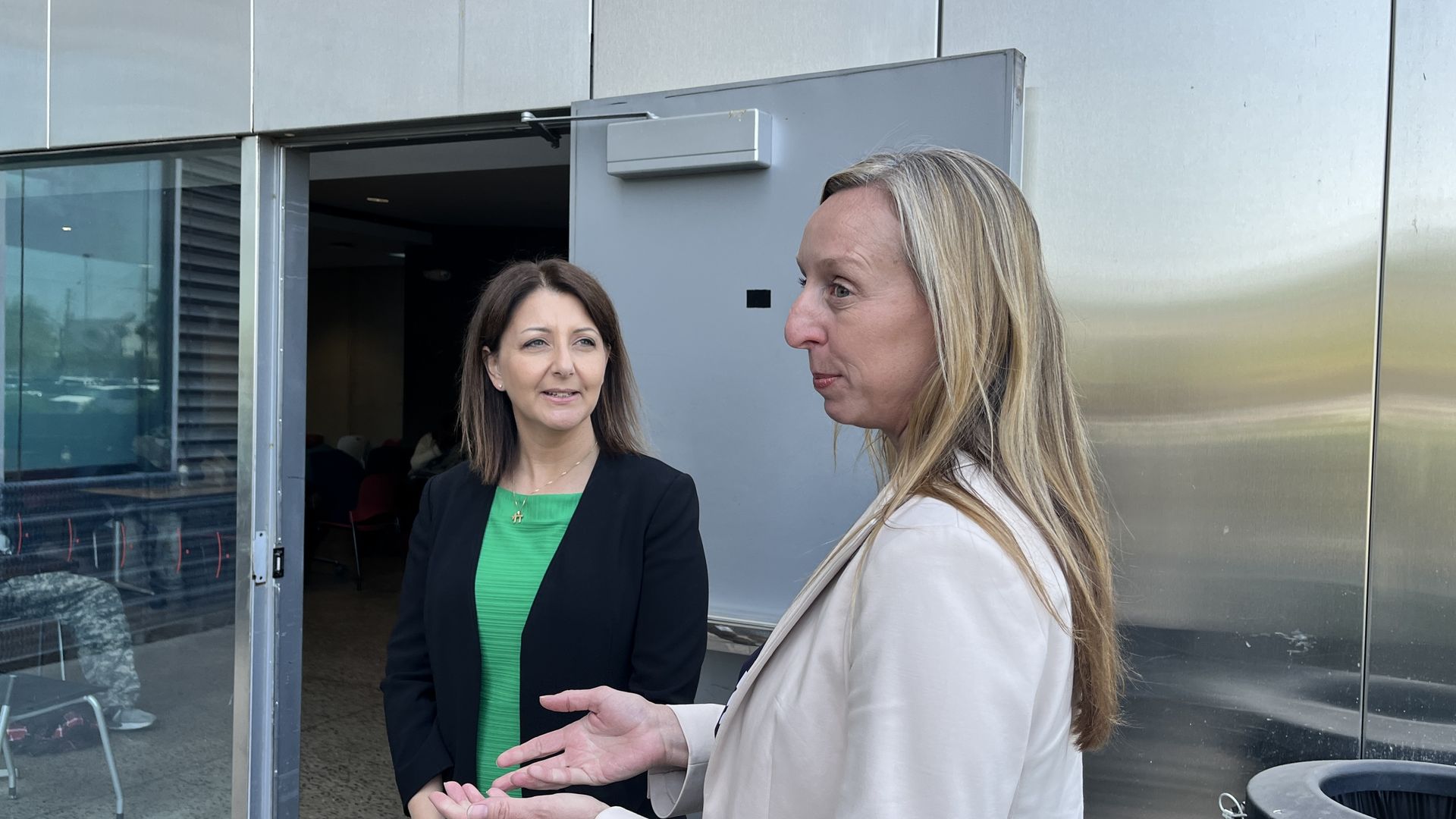Two women standing outside a door.