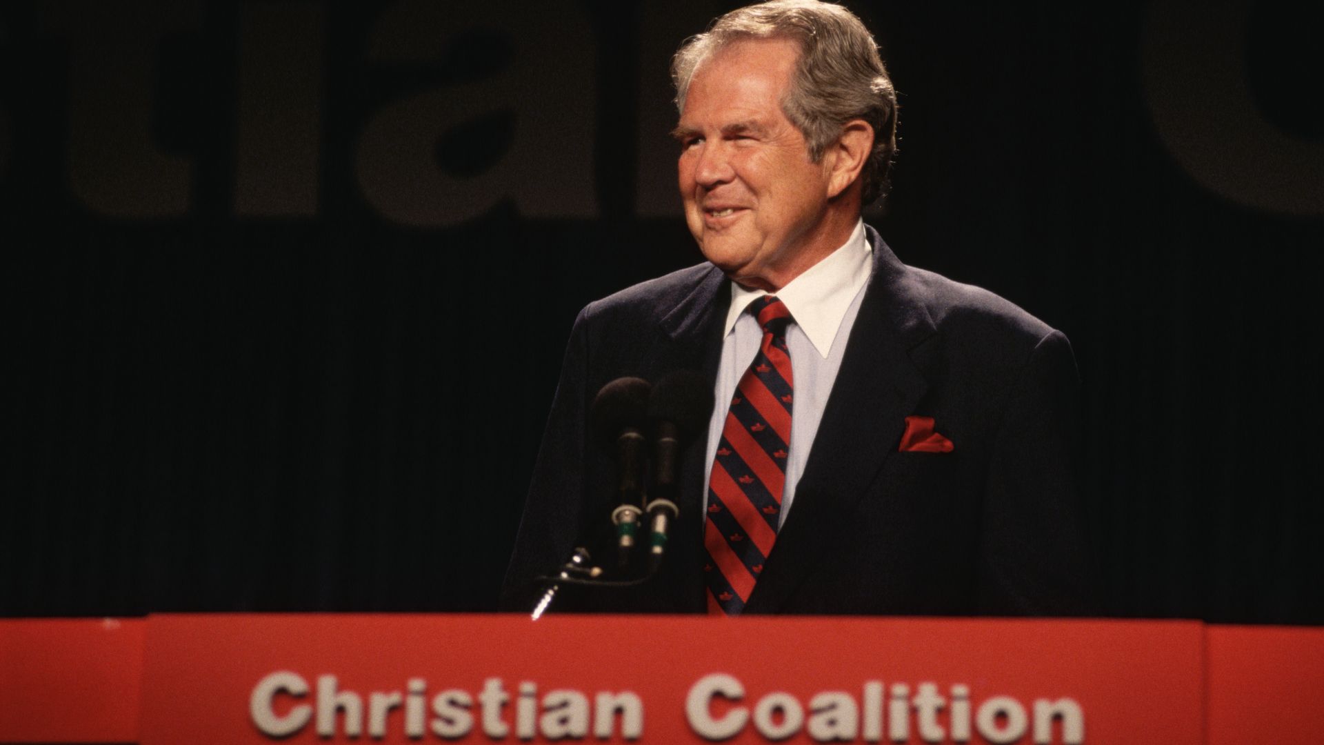 An old photograph of Pat Robertson speaking at a podium with a sign that says "Christian Coalition" underneath it