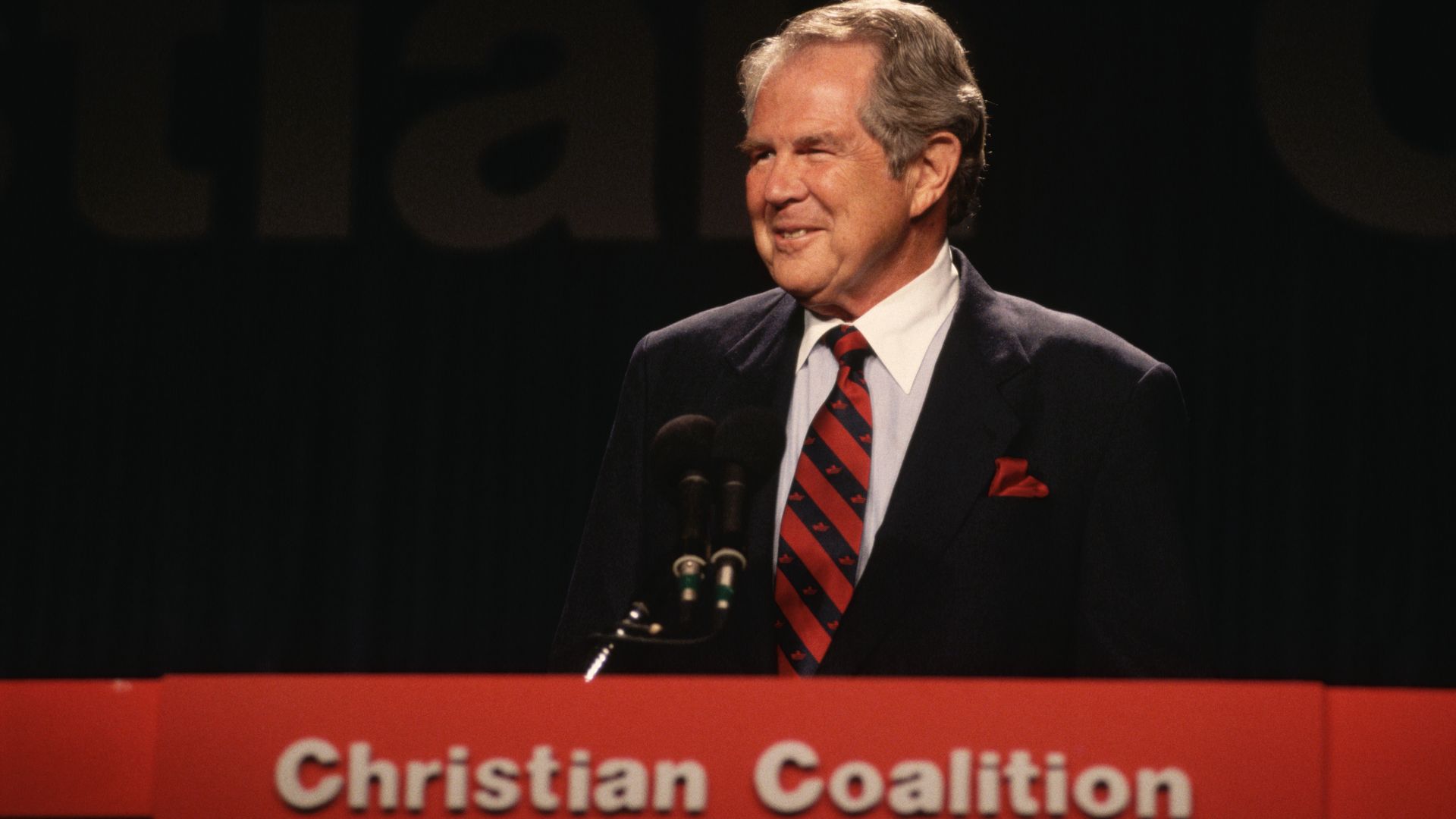 An old photograph of Pat Robertson speaking at a podium with a sign that says "Christian Coalition" underneath it