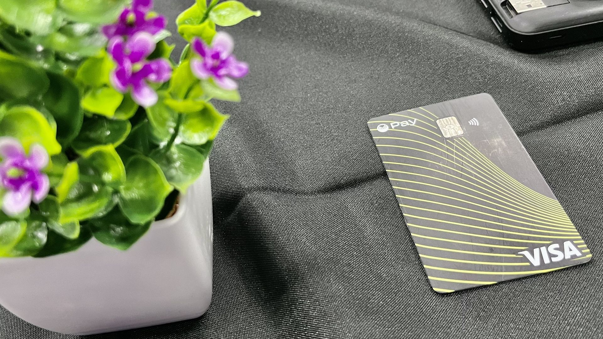 A payment card next to some fake flowers. 