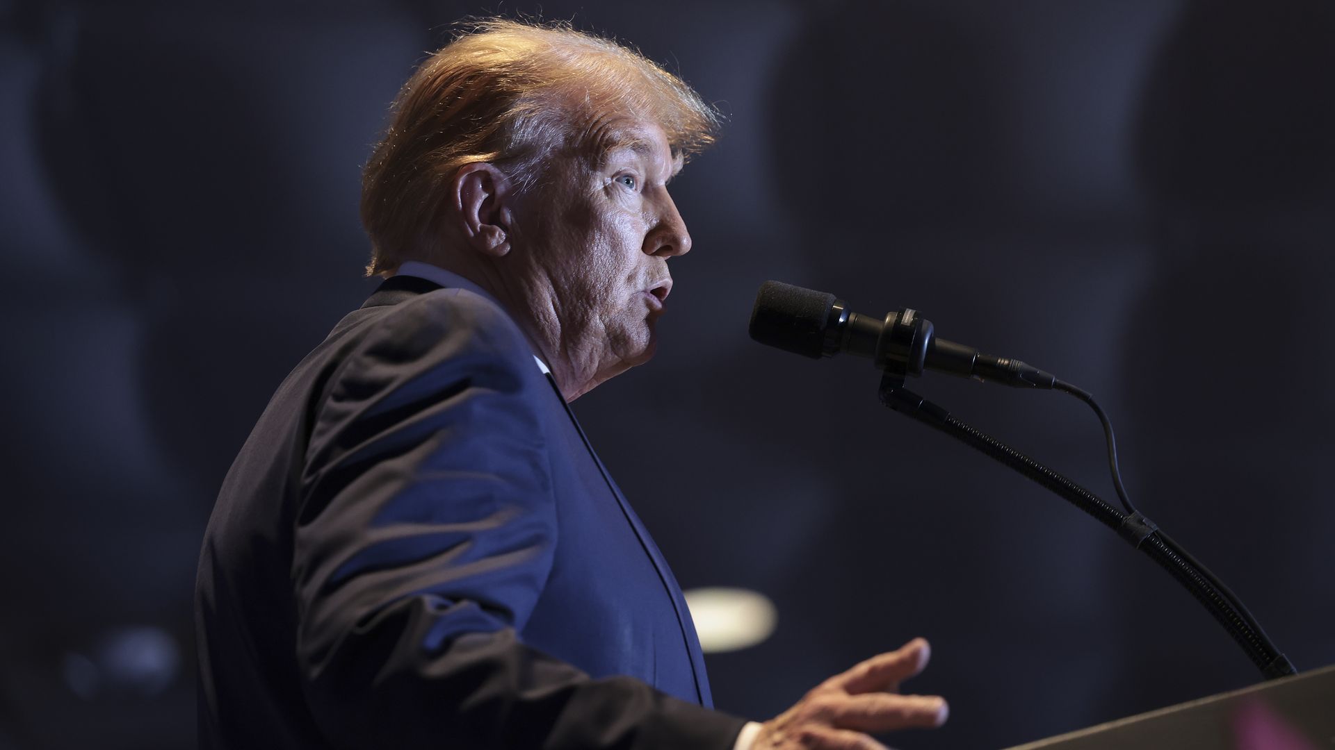 Donald Trump speaks into a microphone at a lectern. 